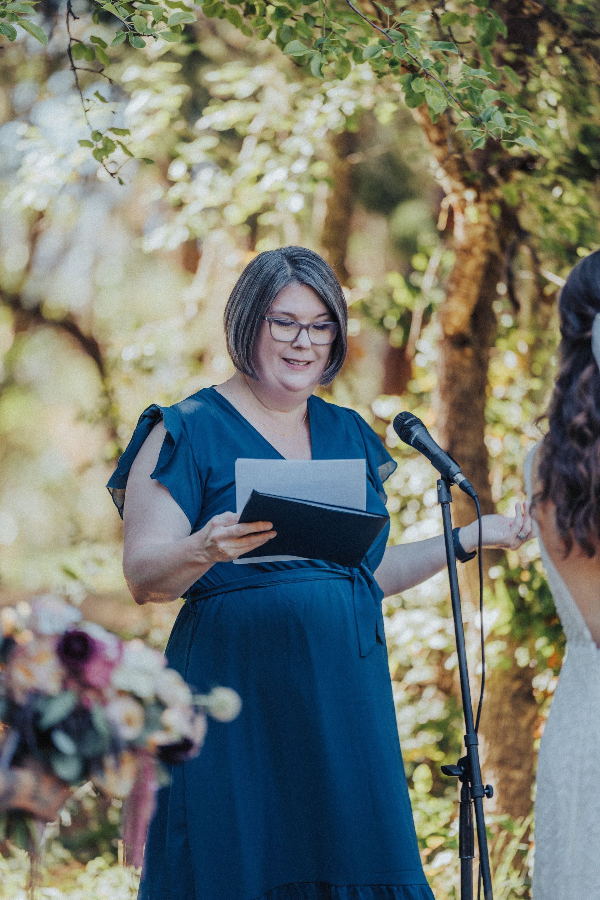 A woman in a blue dress is standing in front of a microphone.
