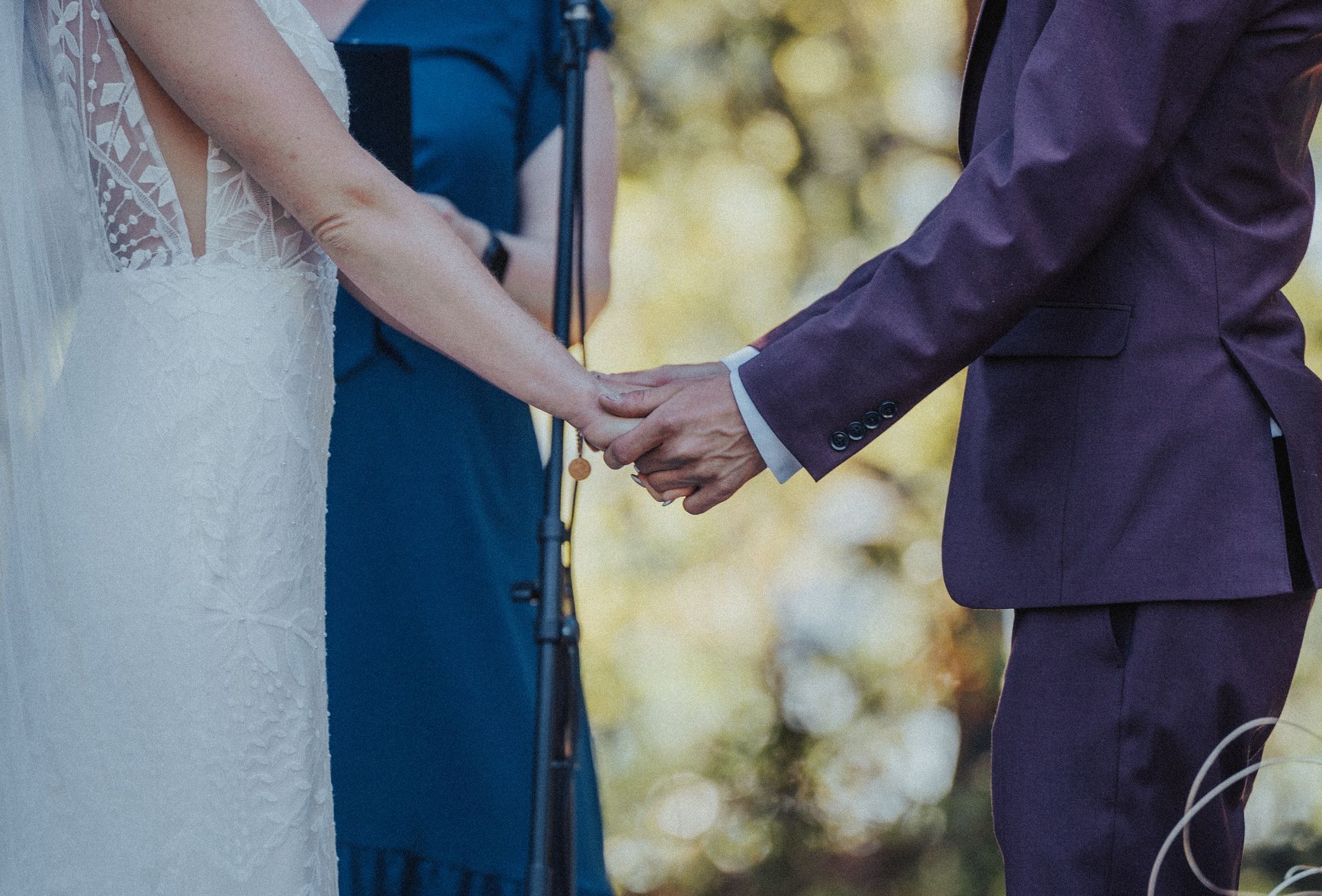 A bride and groom are holding hands during their wedding ceremony.