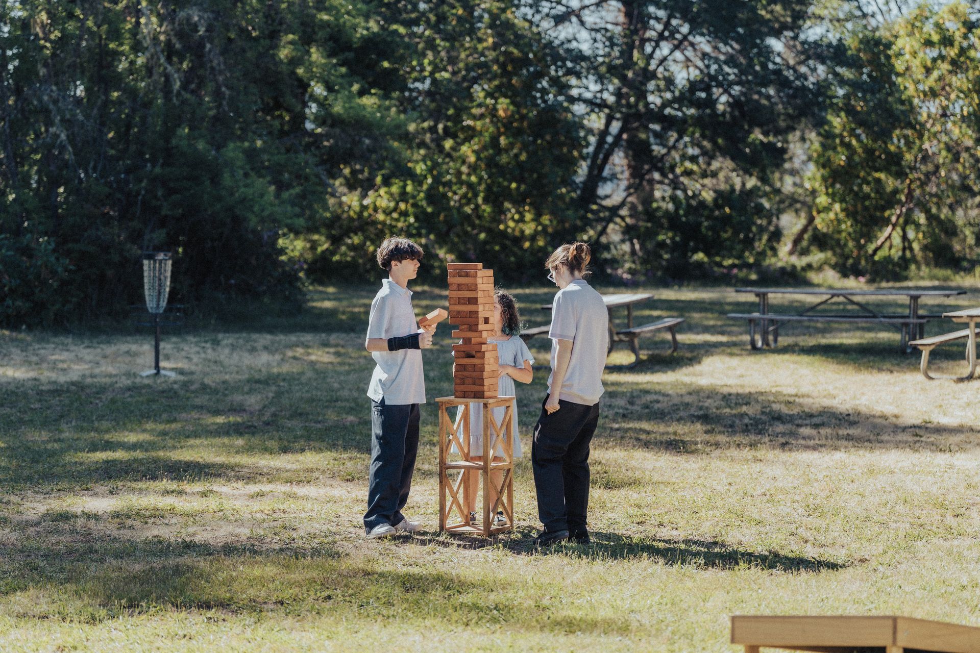 A group of children are playing jenga in a park.