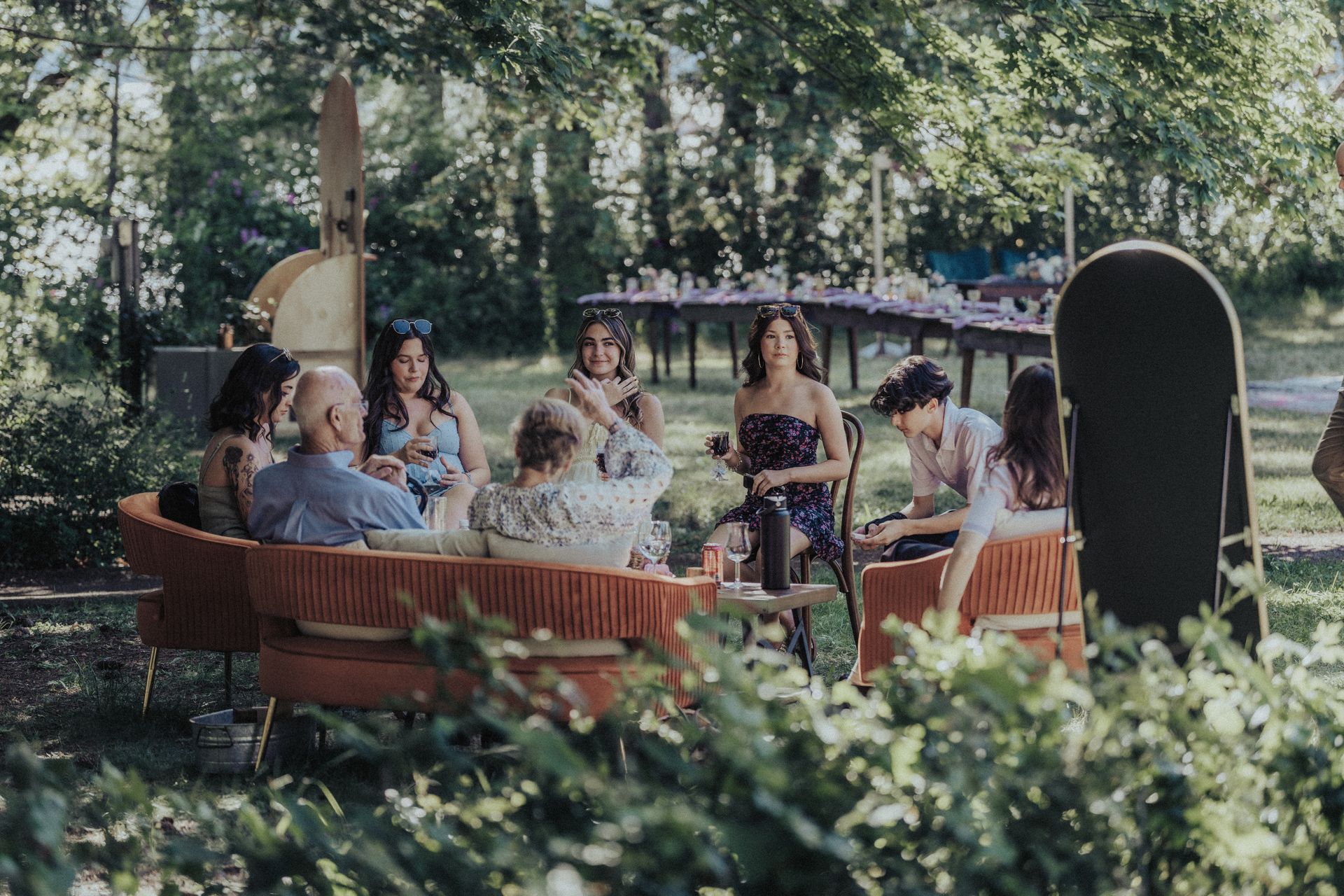 A group of people are sitting around a table in a park.