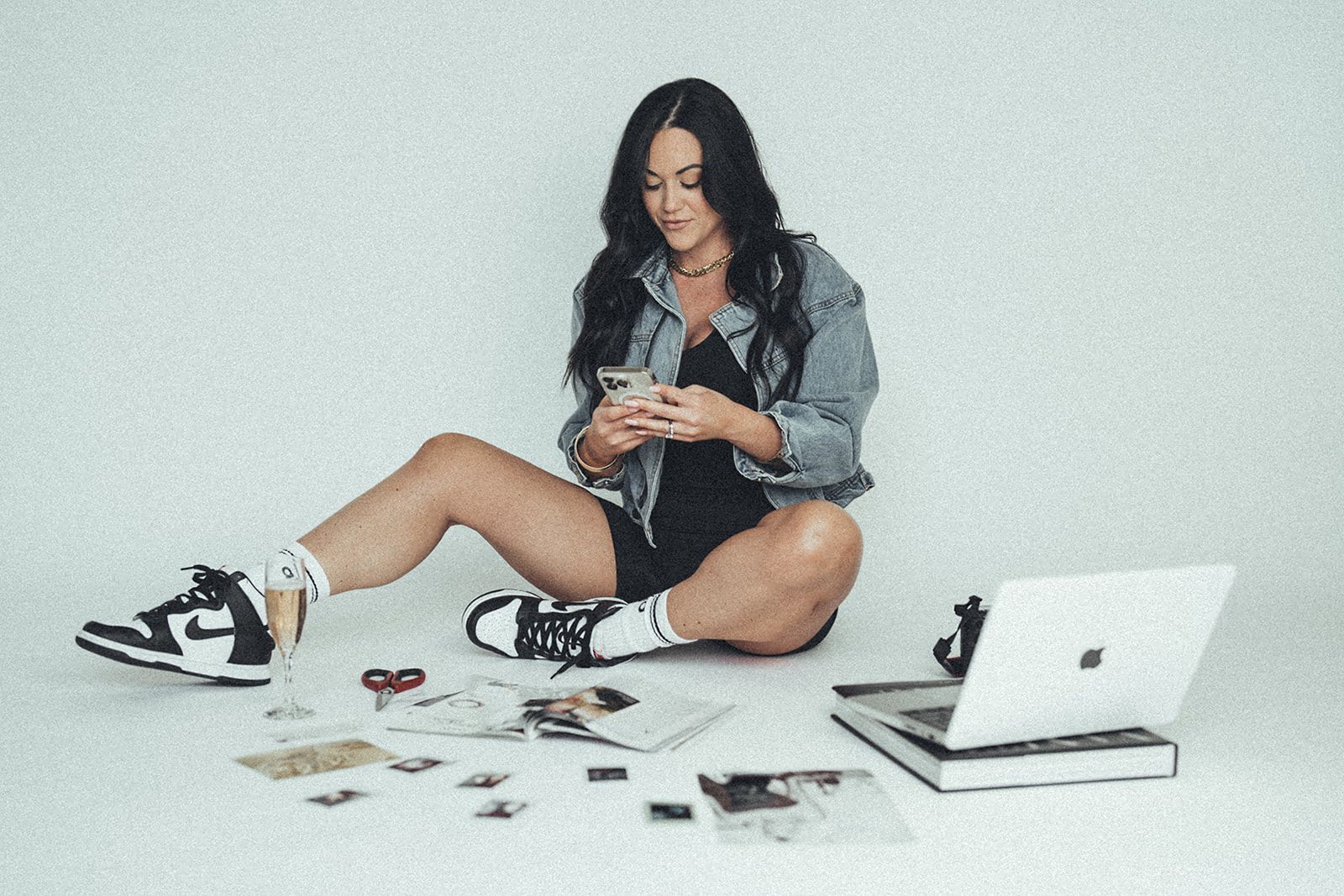 A woman is sitting on the floor looking at her phone.