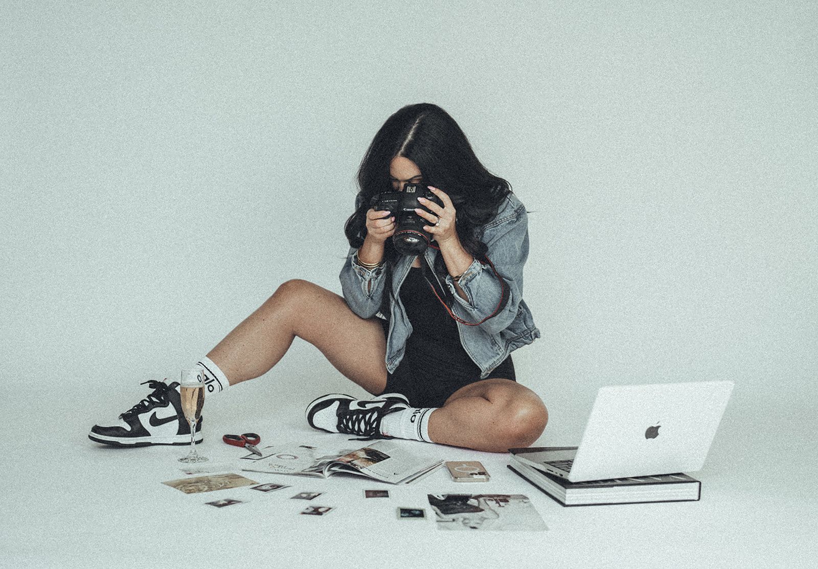 A woman is sitting on the floor taking a picture with a camera.