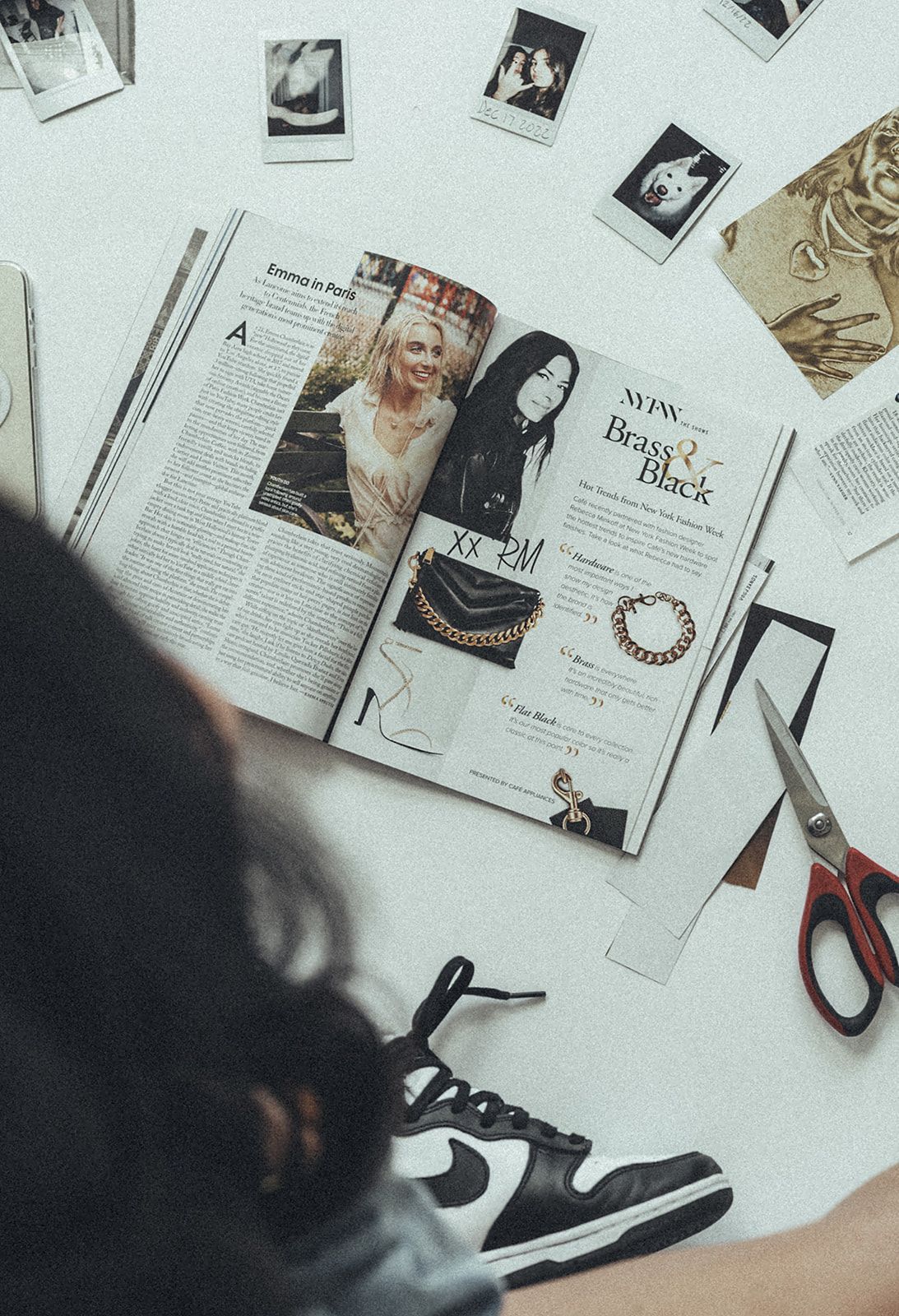 A person is sitting at a table with a magazine and scissors.
