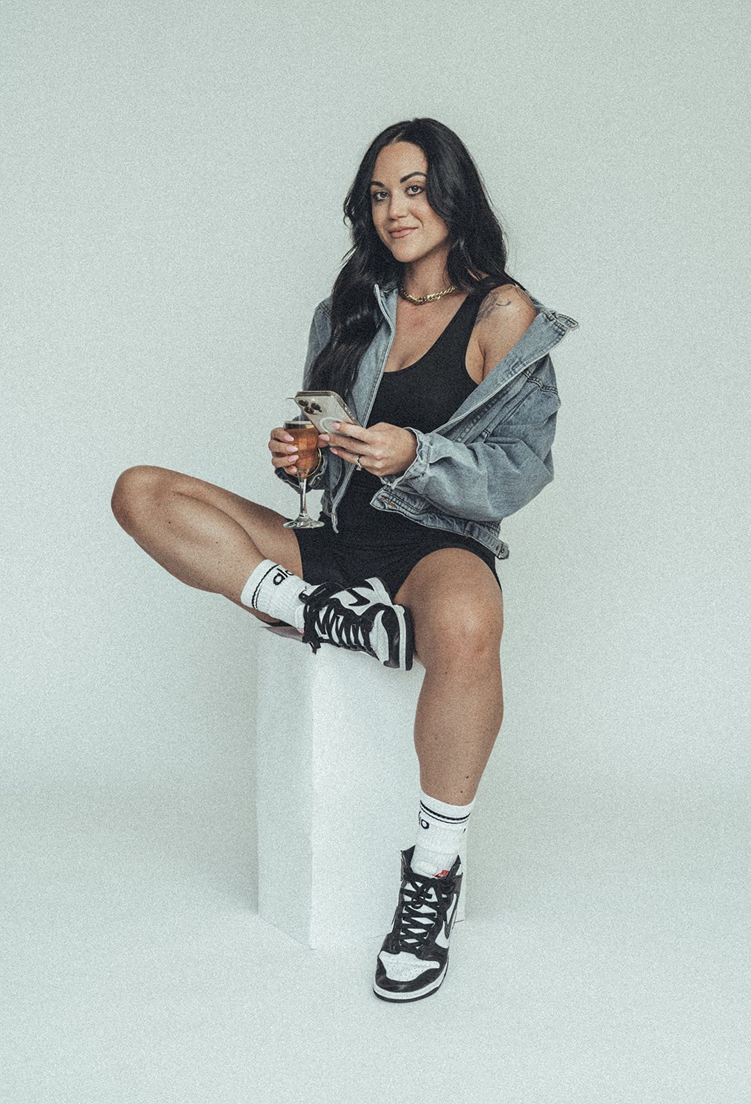 A woman is sitting on a cube holding a glass of wine.