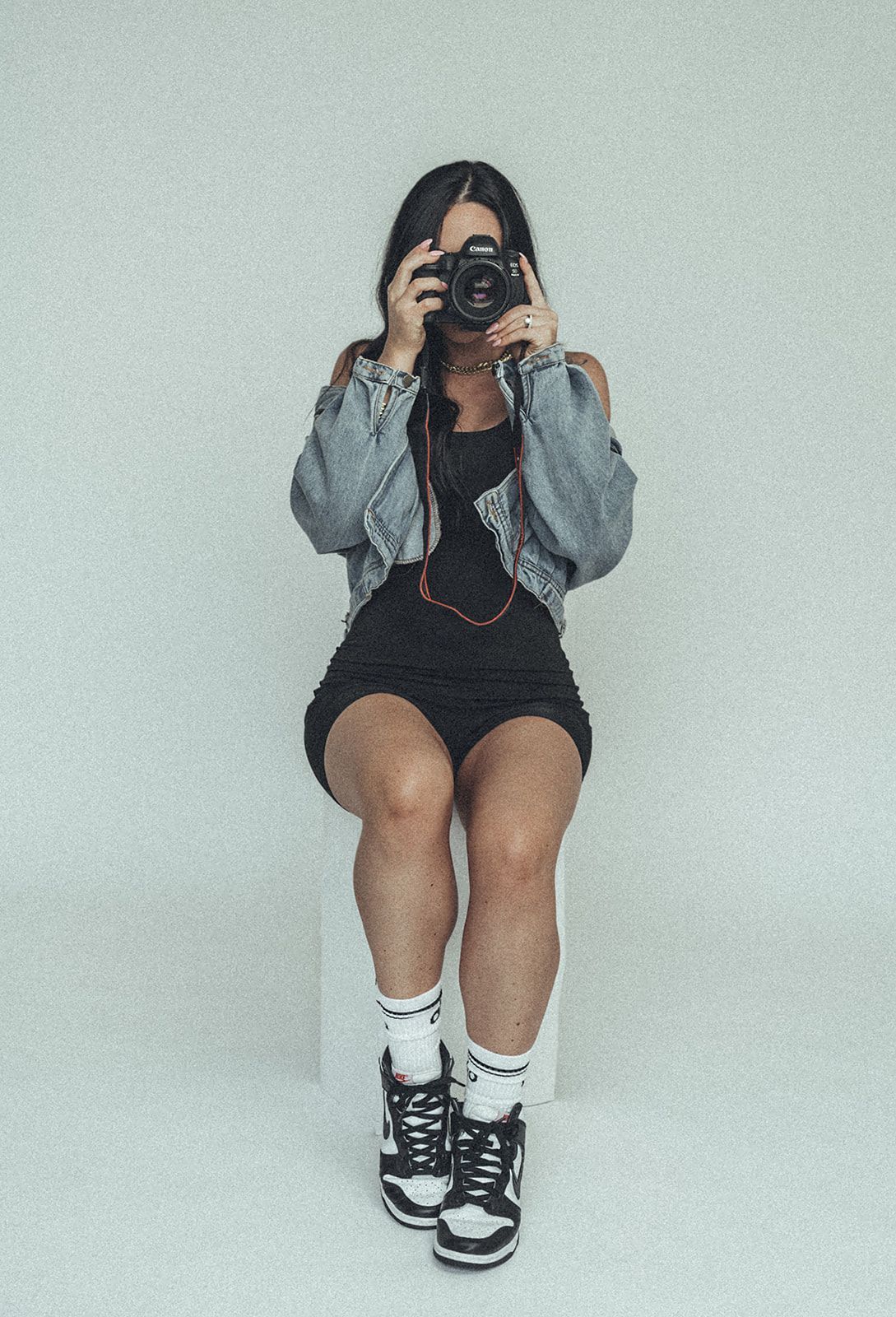 A woman is sitting on a chair taking a picture with a camera.