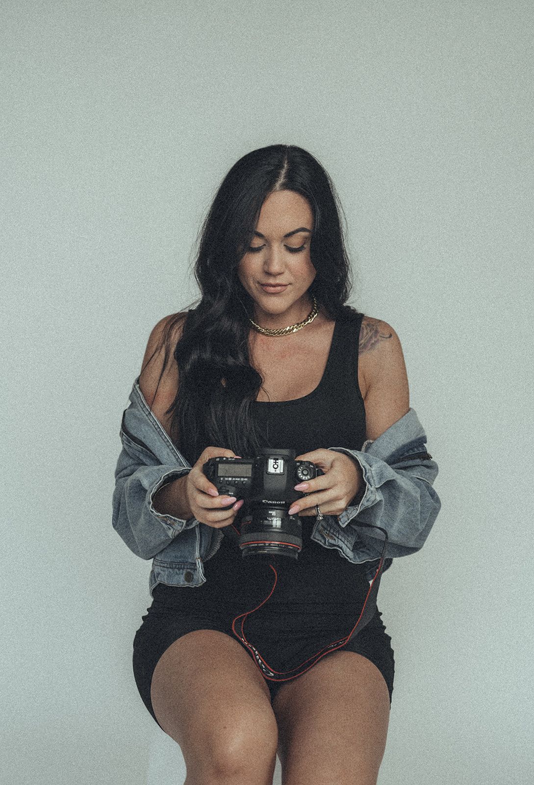 A woman is sitting on a stool holding a camera.