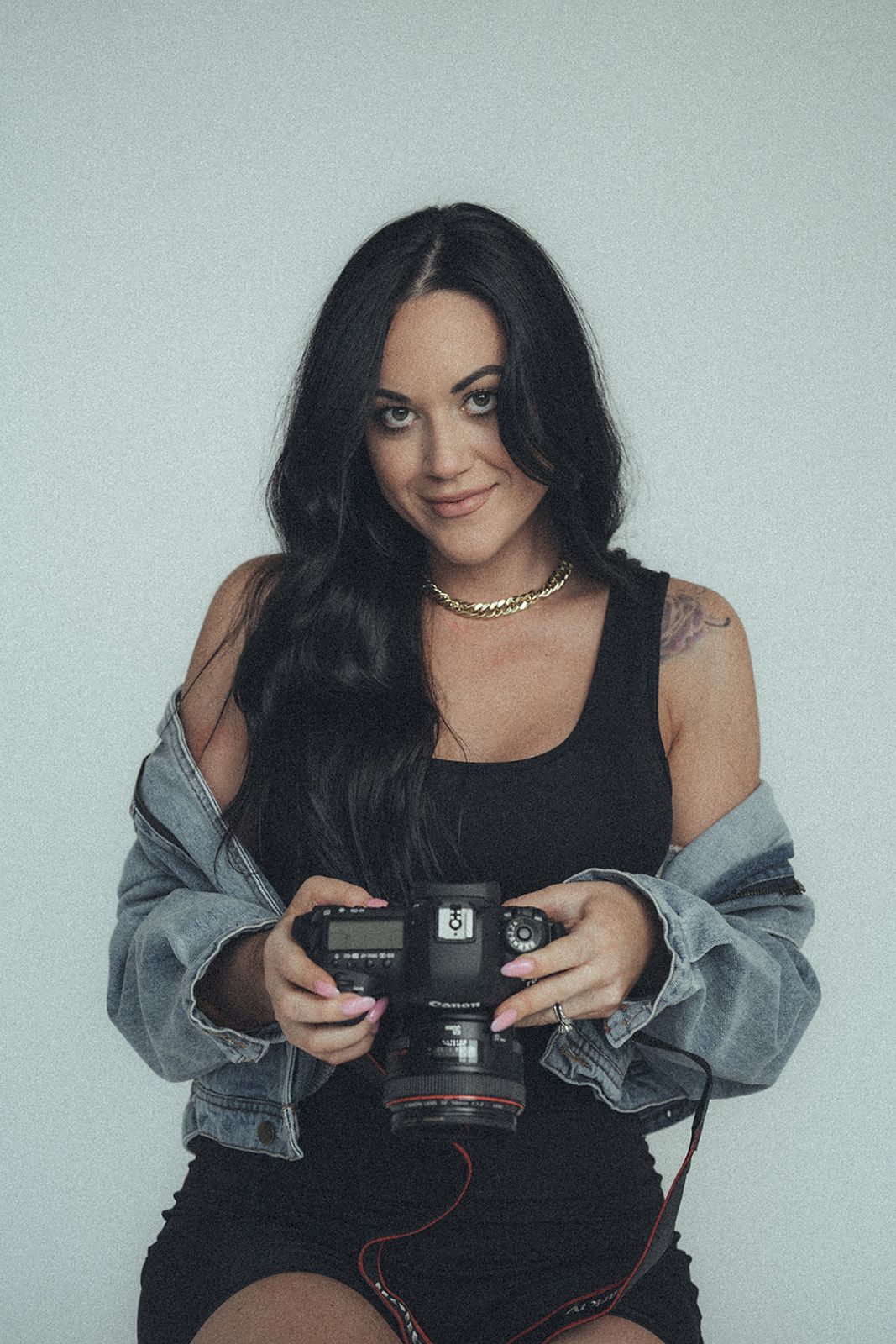 A woman is sitting on a chair holding a camera.