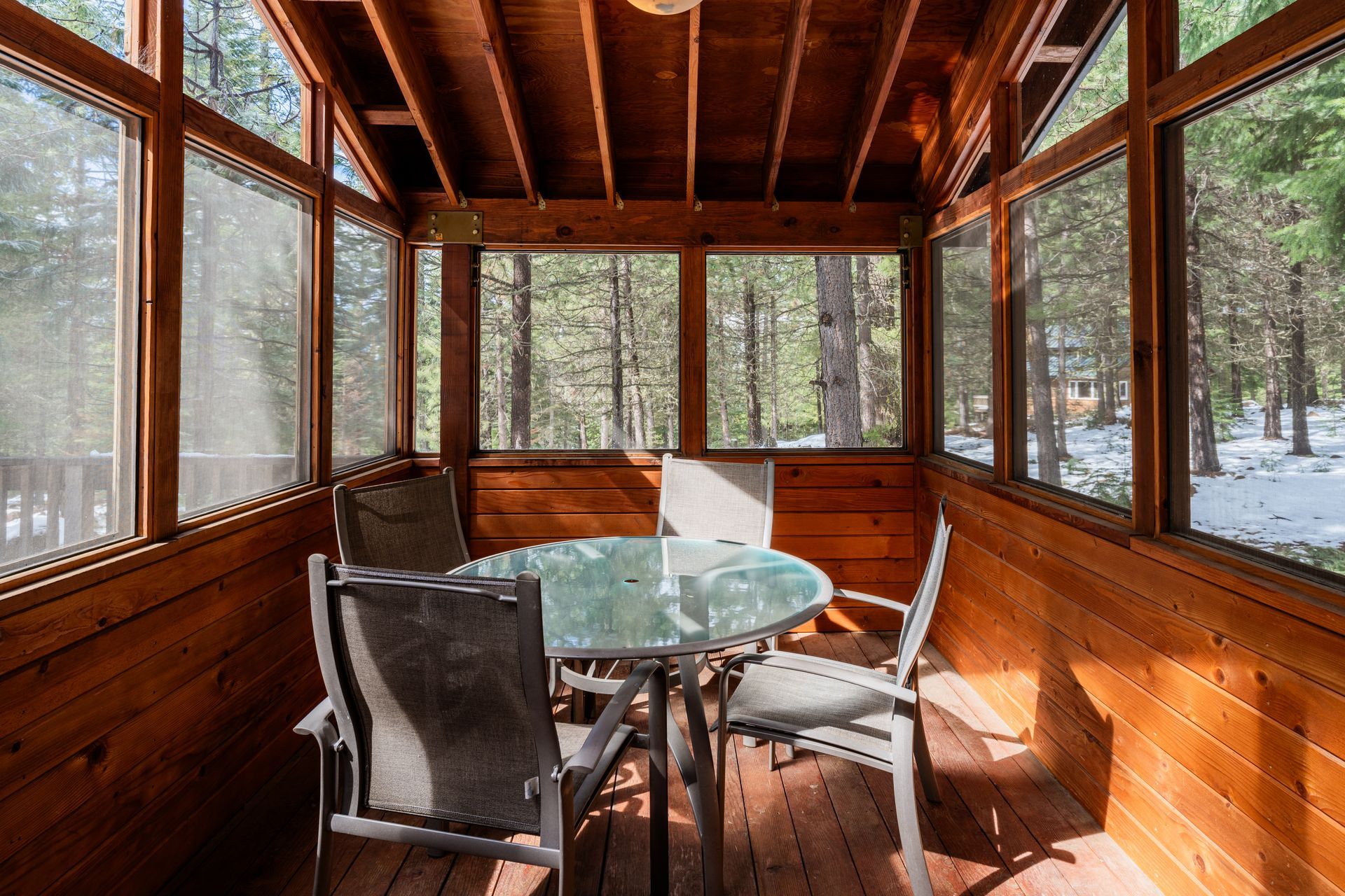 A screened in porch with a table and chairs in it.