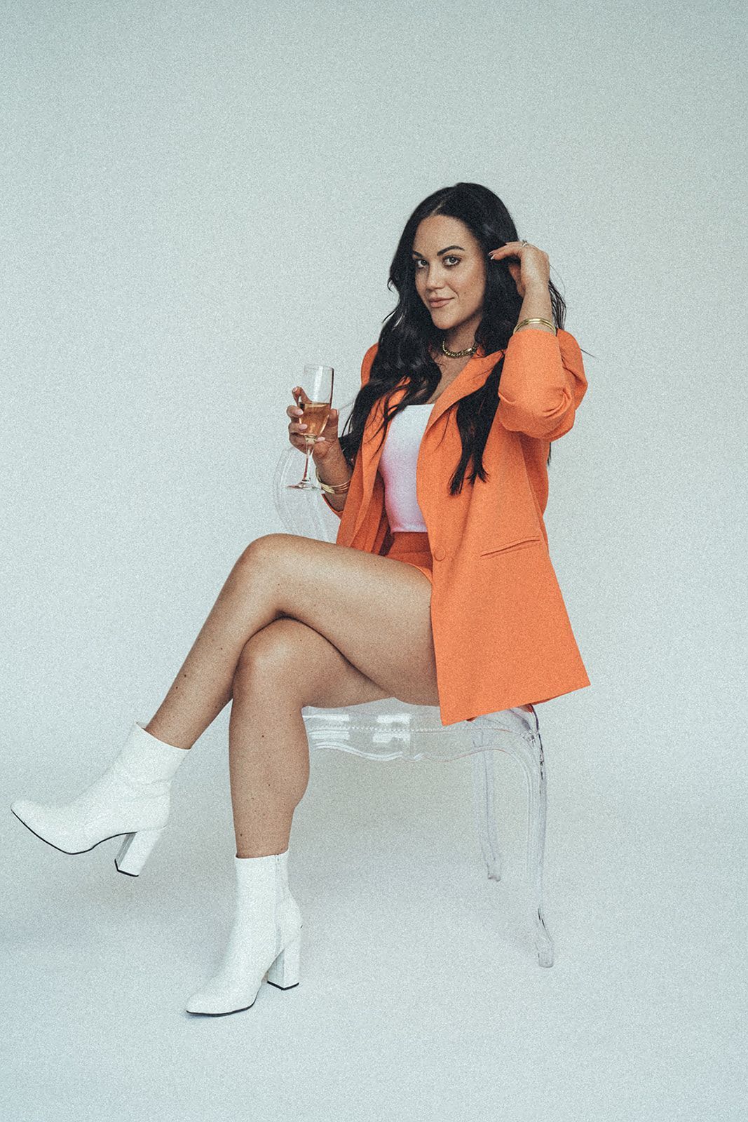 A woman is sitting on a chair holding a glass of wine.