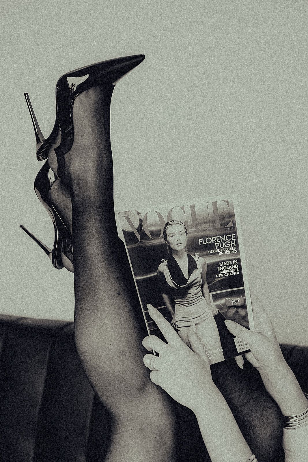A black and white photo of a woman reading a magazine