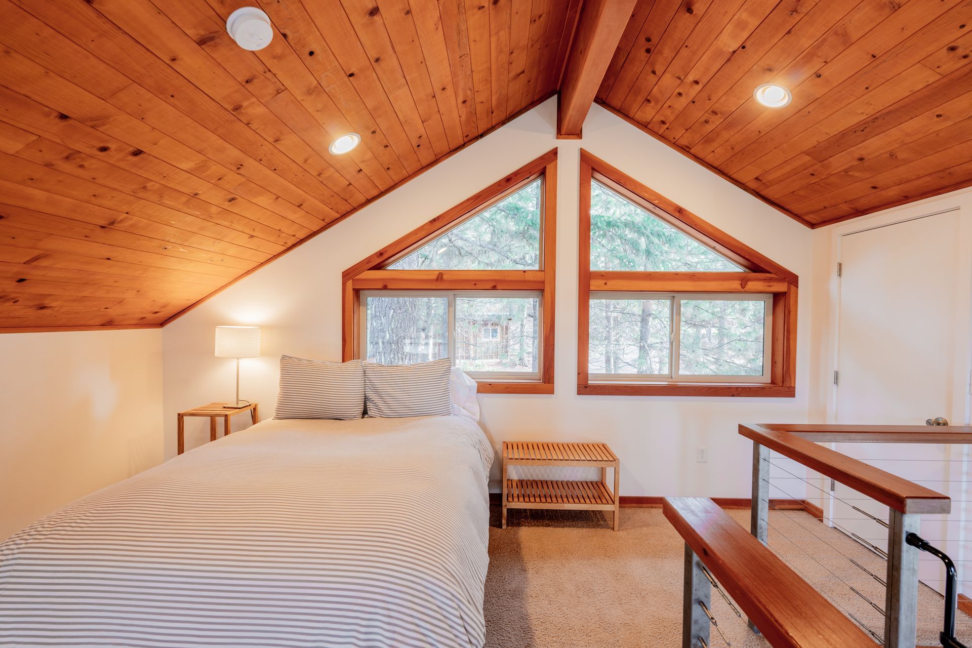 There is a bed in the attic with a wooden ceiling.