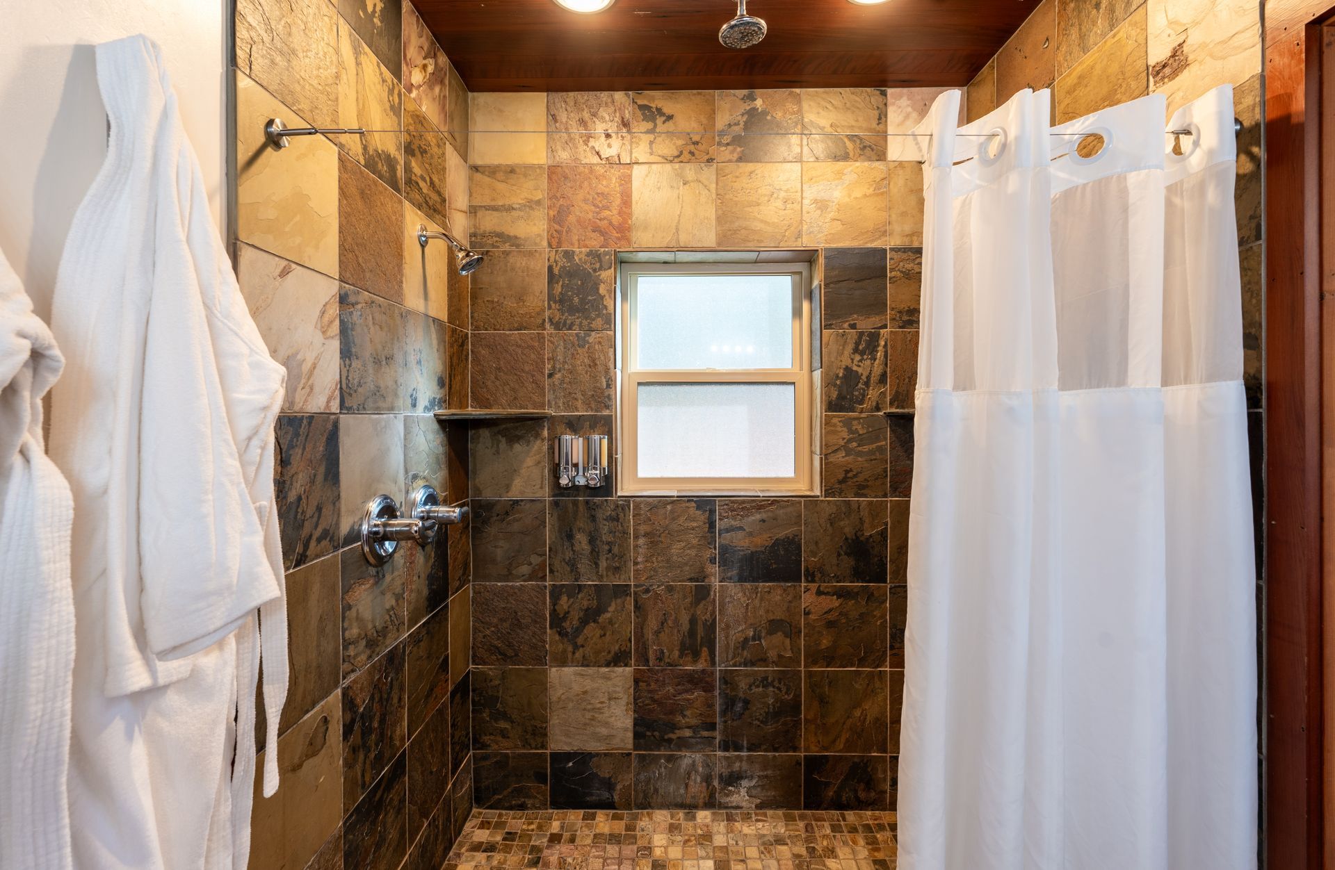 A bathroom with a walk in shower and a window.