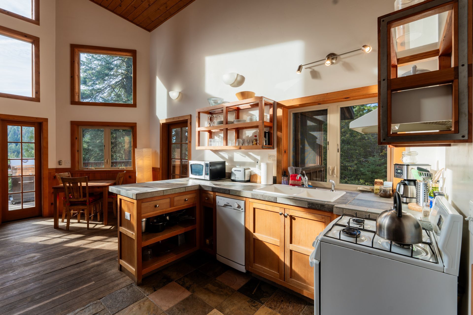 A kitchen in a house with a lot of windows and wooden cabinets.