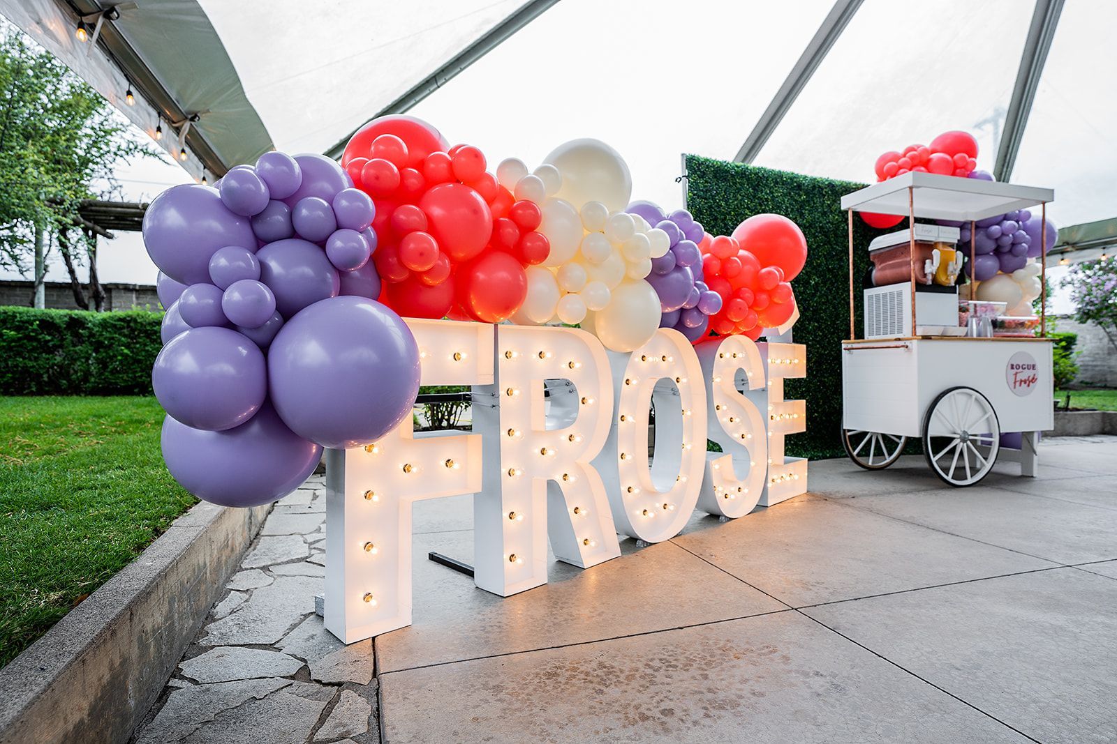 A sign that says `` frose '' is surrounded by balloons.