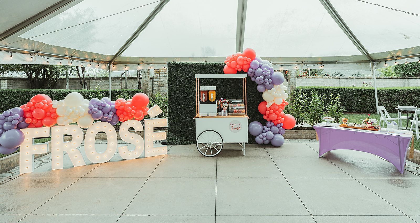 A large sign that says `` frose '' is lit up in a room with balloons.