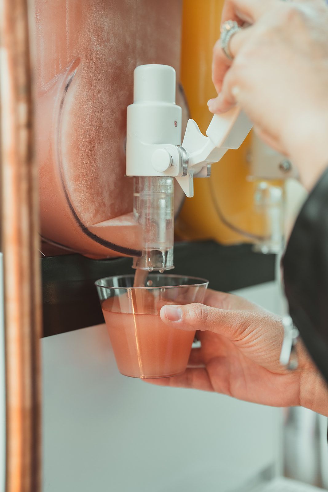 A person is pouring juice into a cup from a dispenser.