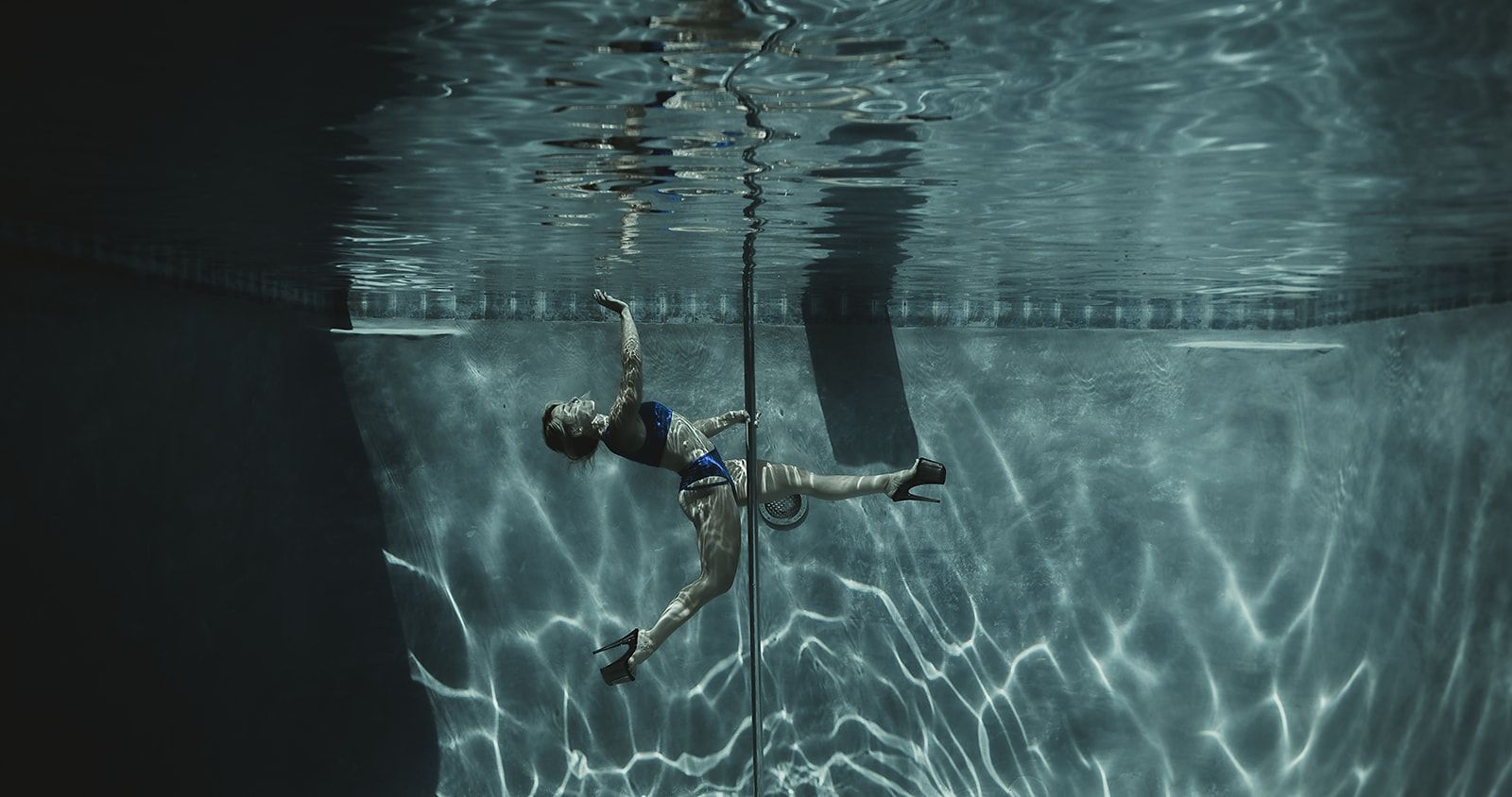 A woman is doing aerial acrobatics in a swimming pool.