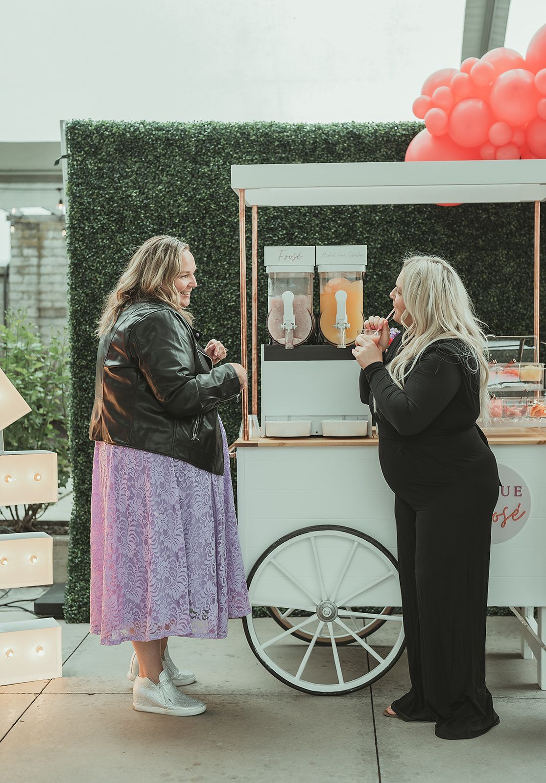 Two women are standing next to each other in front of a food cart.