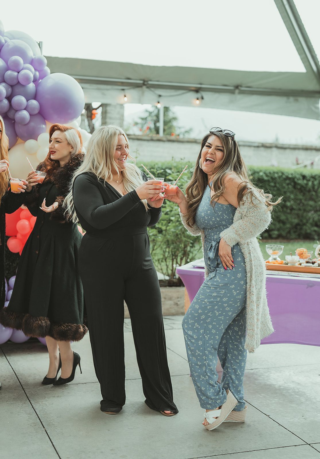A group of women are standing next to each other holding drinks.