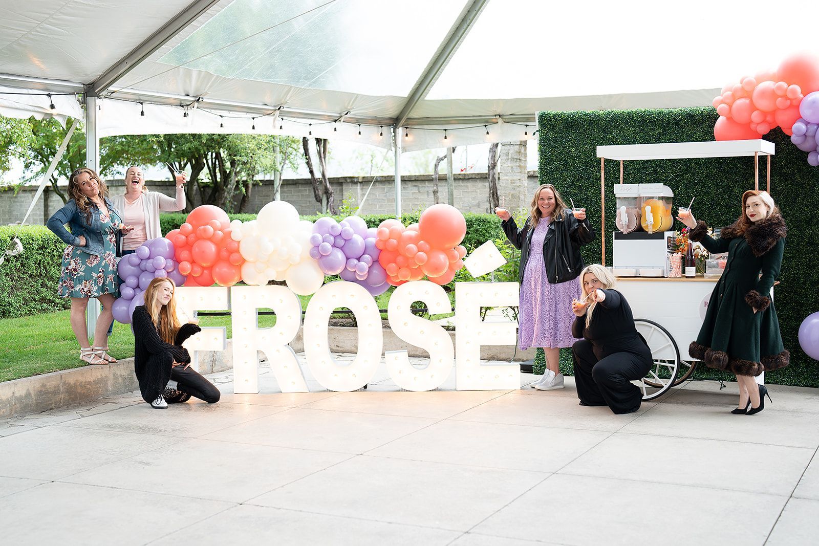 A group of women are posing for a picture in front of a large sign that says erose.