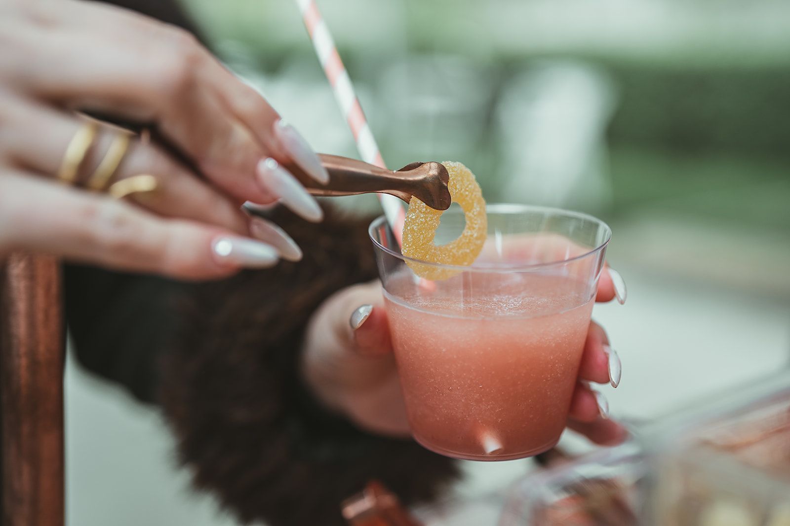 A woman is pouring a drink into a cup with a straw.
