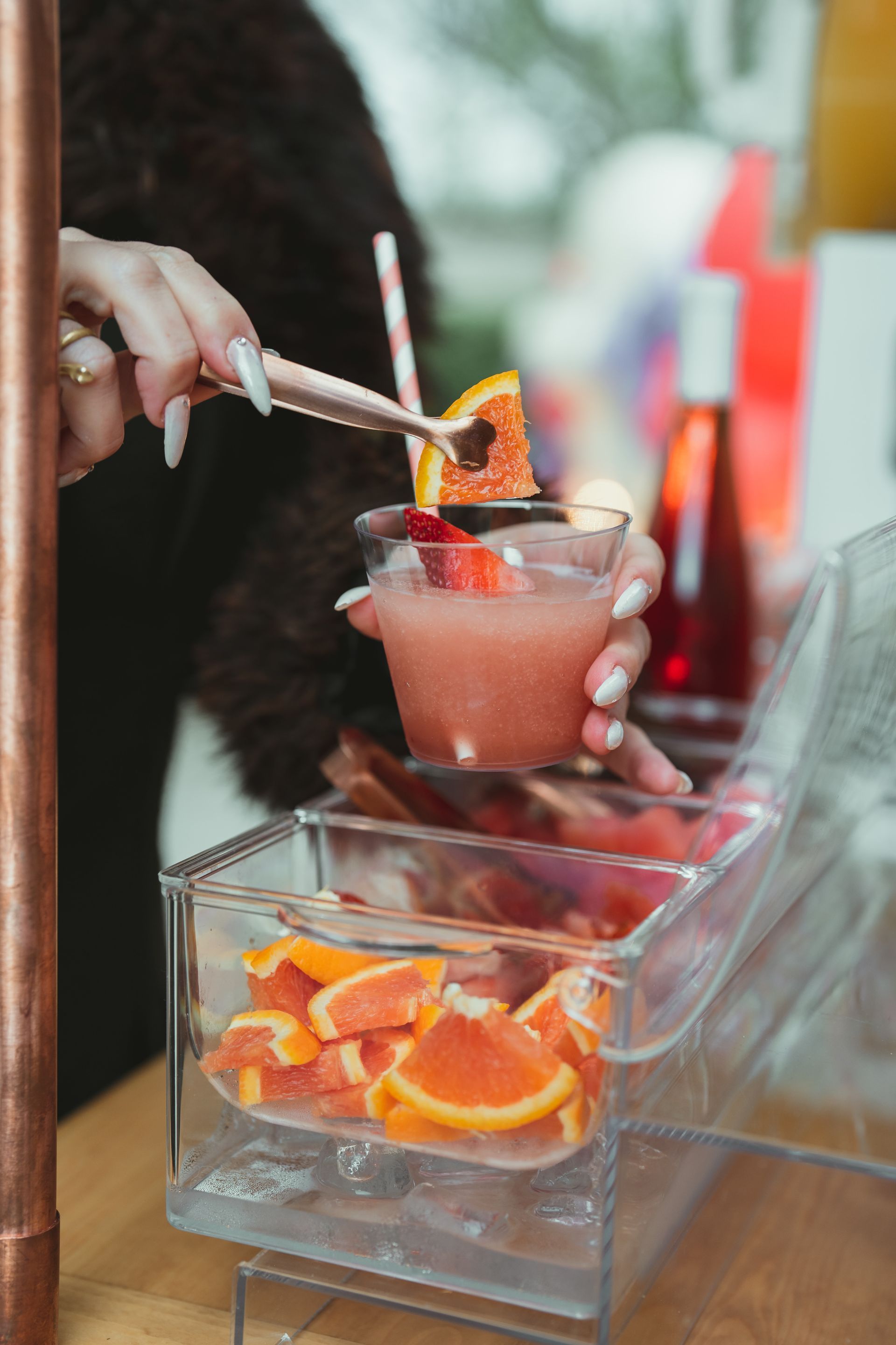 A woman is pouring a drink into a glass with a straw.