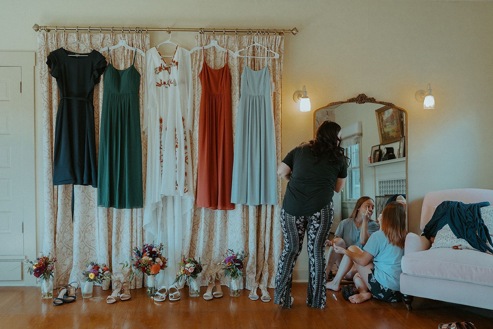 A group of women are standing in front of a wall with dresses hanging on it.