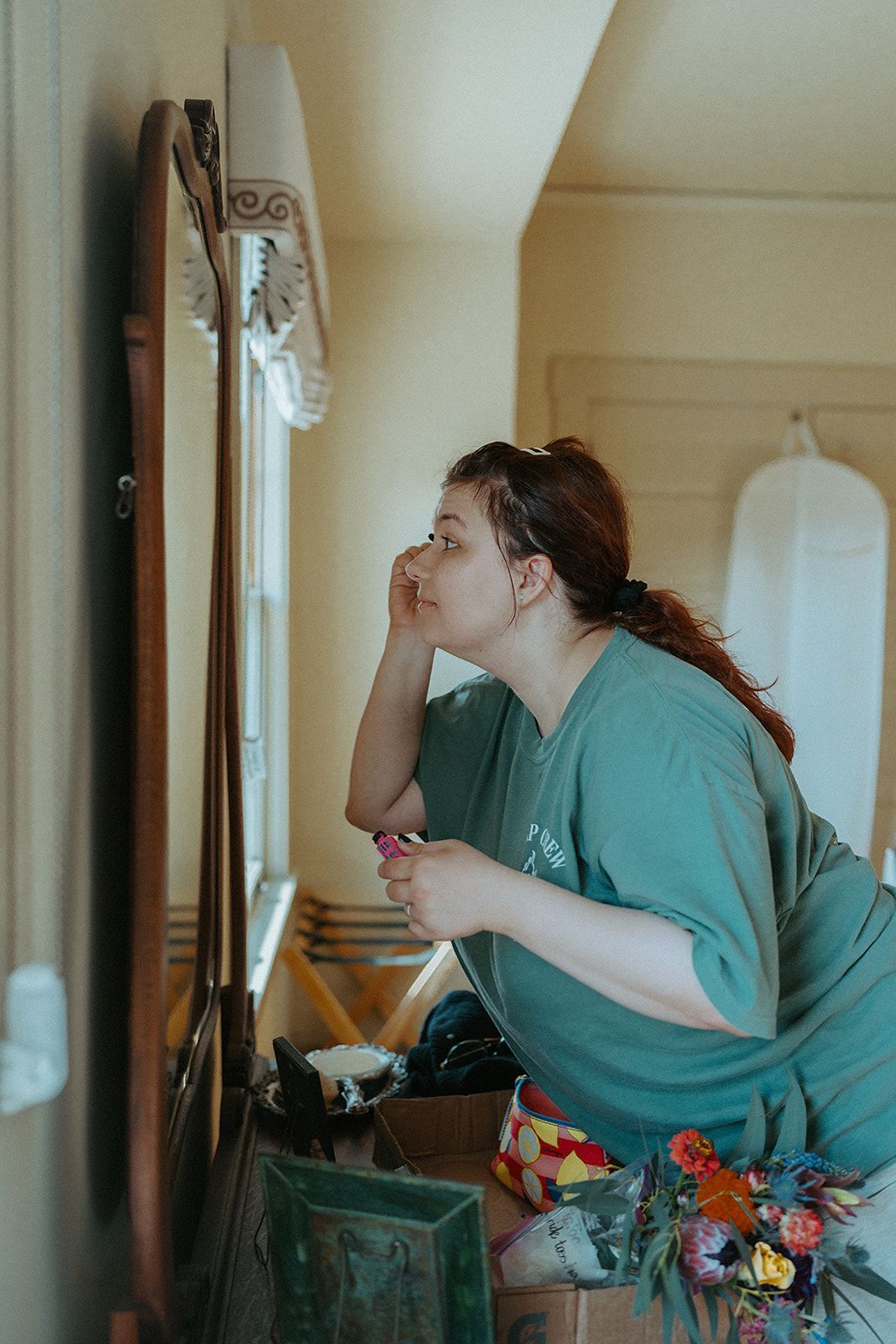 A woman is looking at herself in a mirror in a bathroom.
