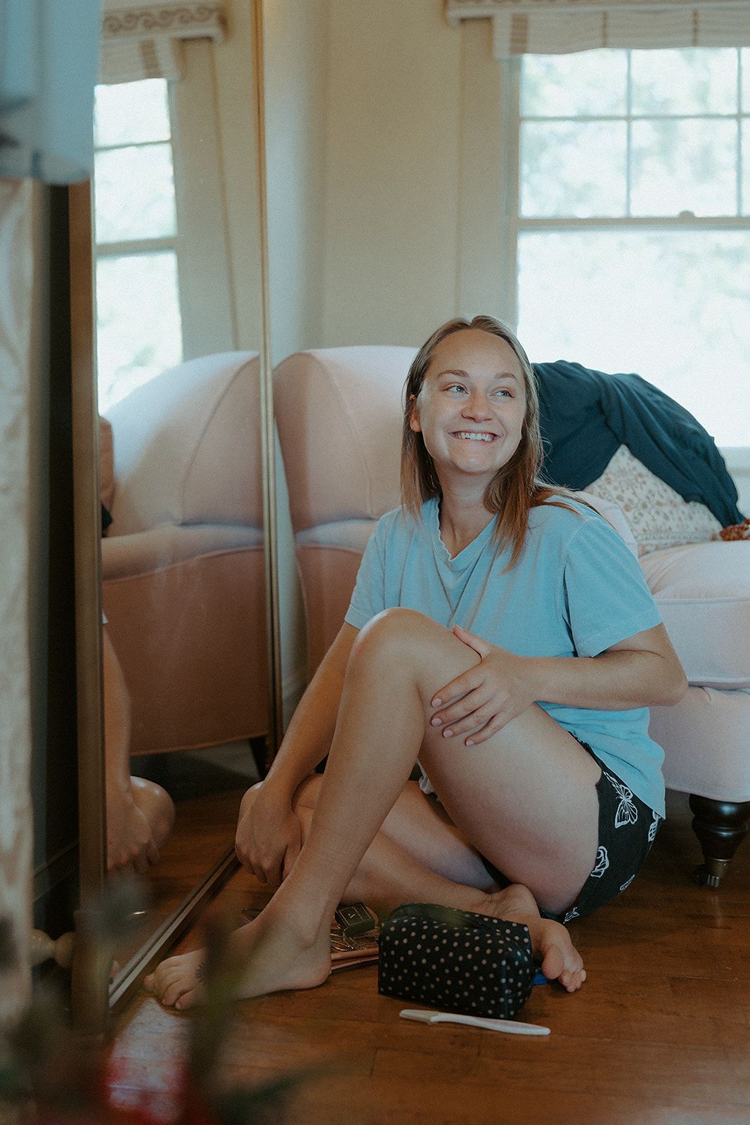 A woman is sitting on the floor in front of a mirror.