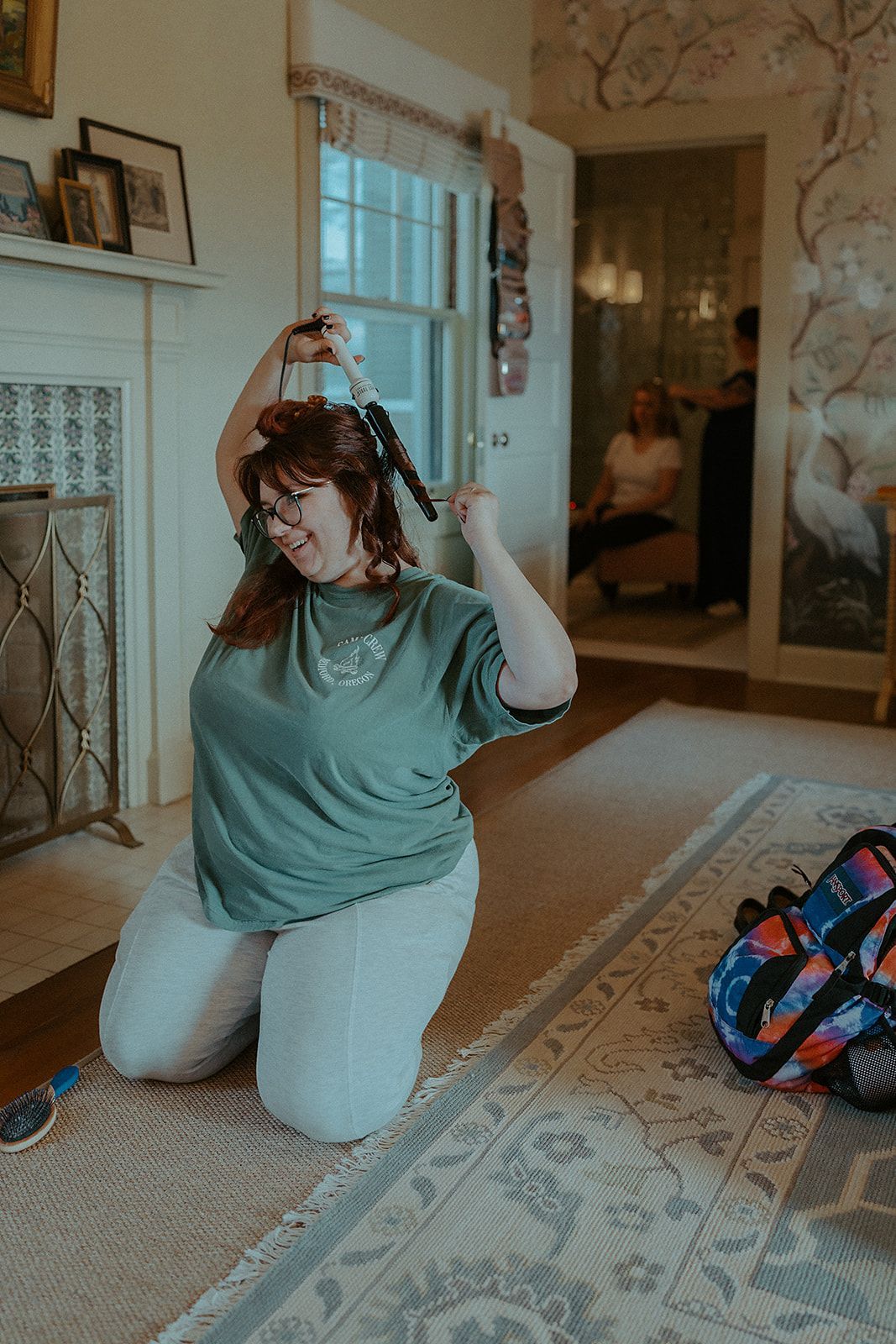 A woman is kneeling on the floor in a living room holding a pair of scissors.
