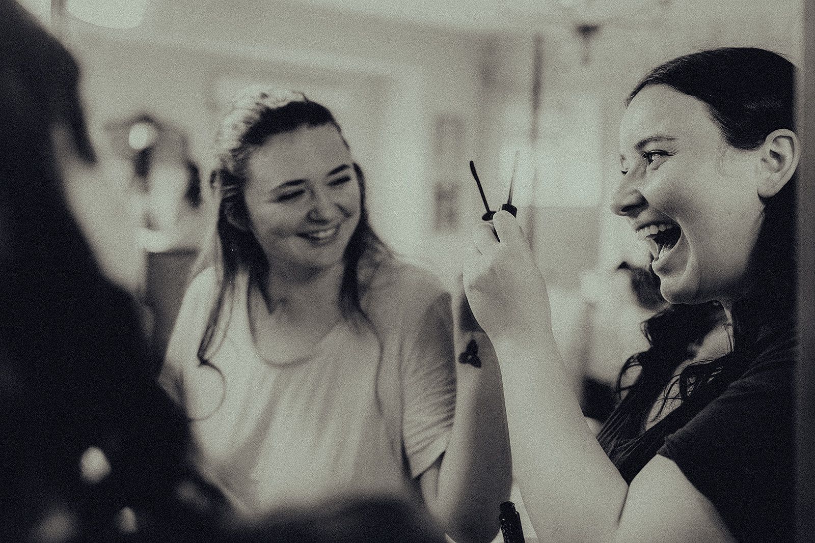 Two women are laughing together in a black and white photo.