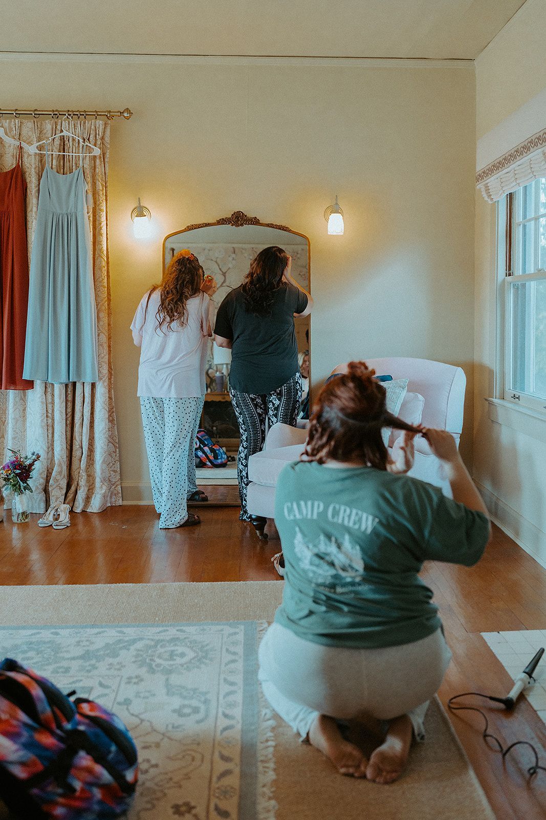 Two women are getting ready for a wedding in a room.