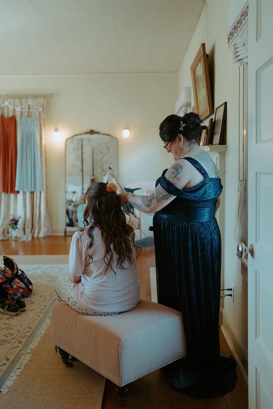 A woman is brushing a girl 's hair in a room.