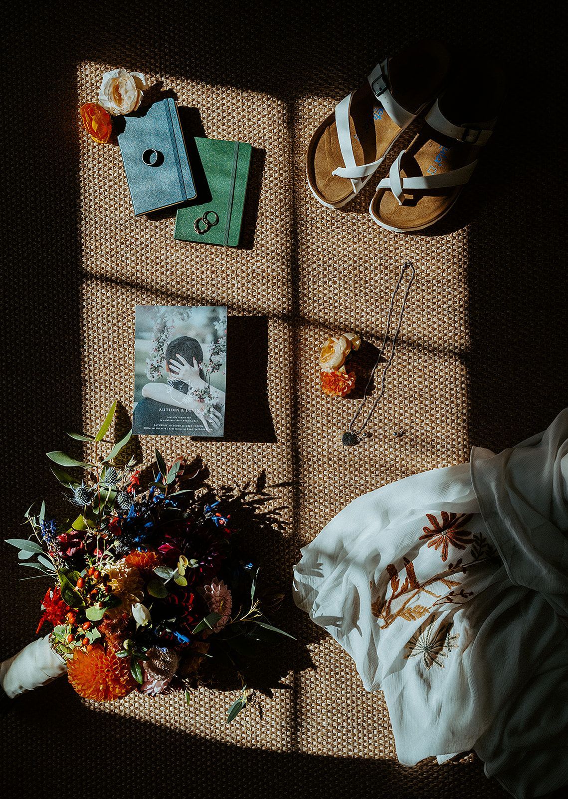 A bride in a wedding dress is sitting on a rug next to a bouquet of flowers.