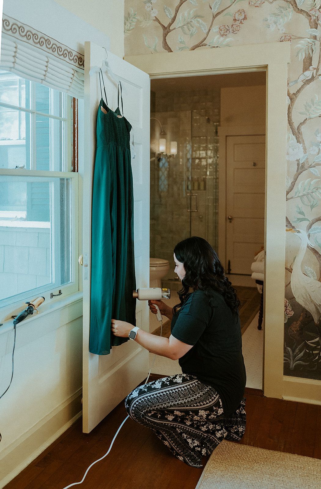 A woman is kneeling down in a room holding a green dress.
