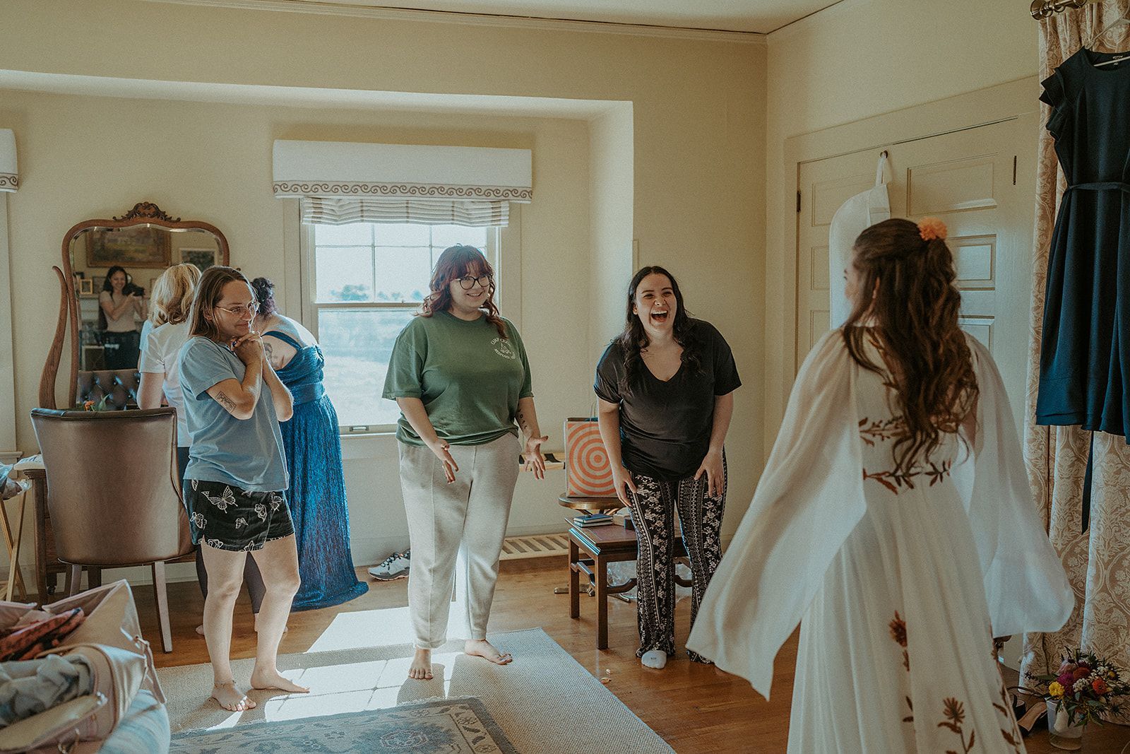 A group of women are standing around a woman in a white dress in a room.