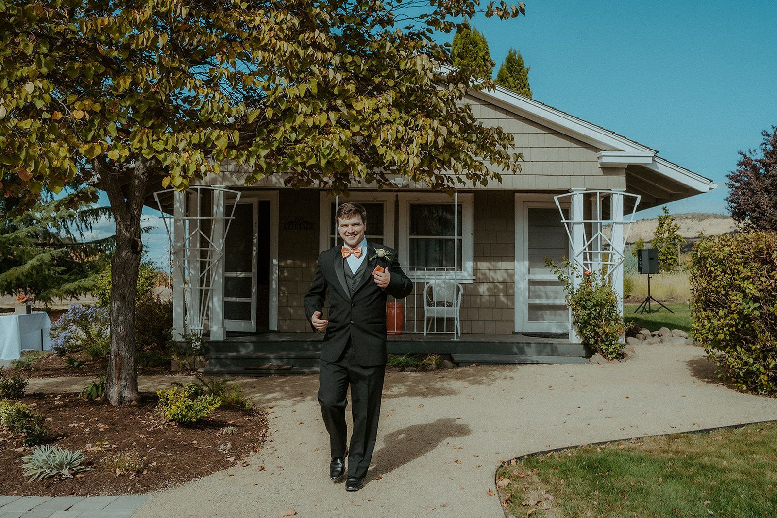 A man in a suit is walking in front of a small house.