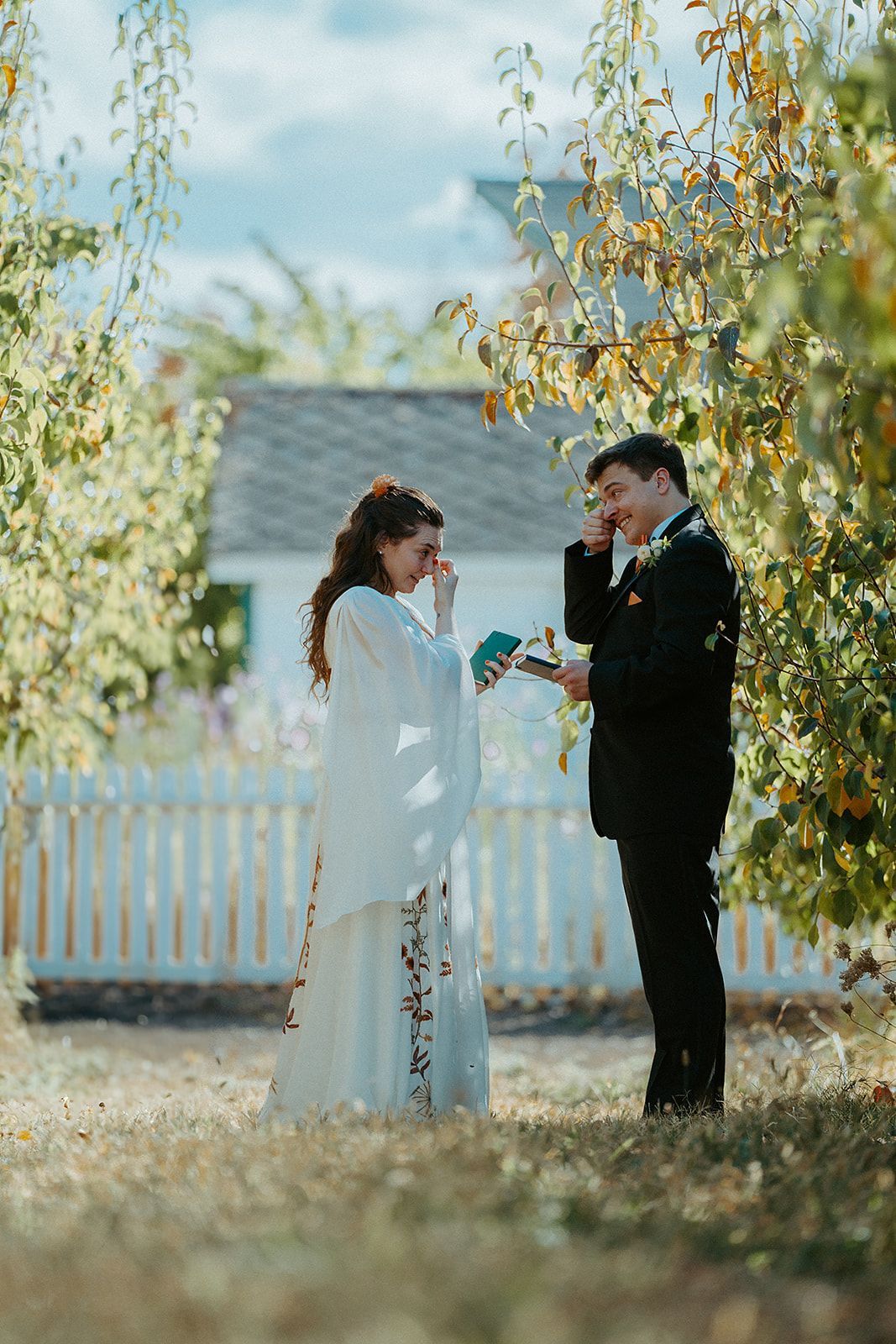 A bride and groom are standing next to each other in a field.