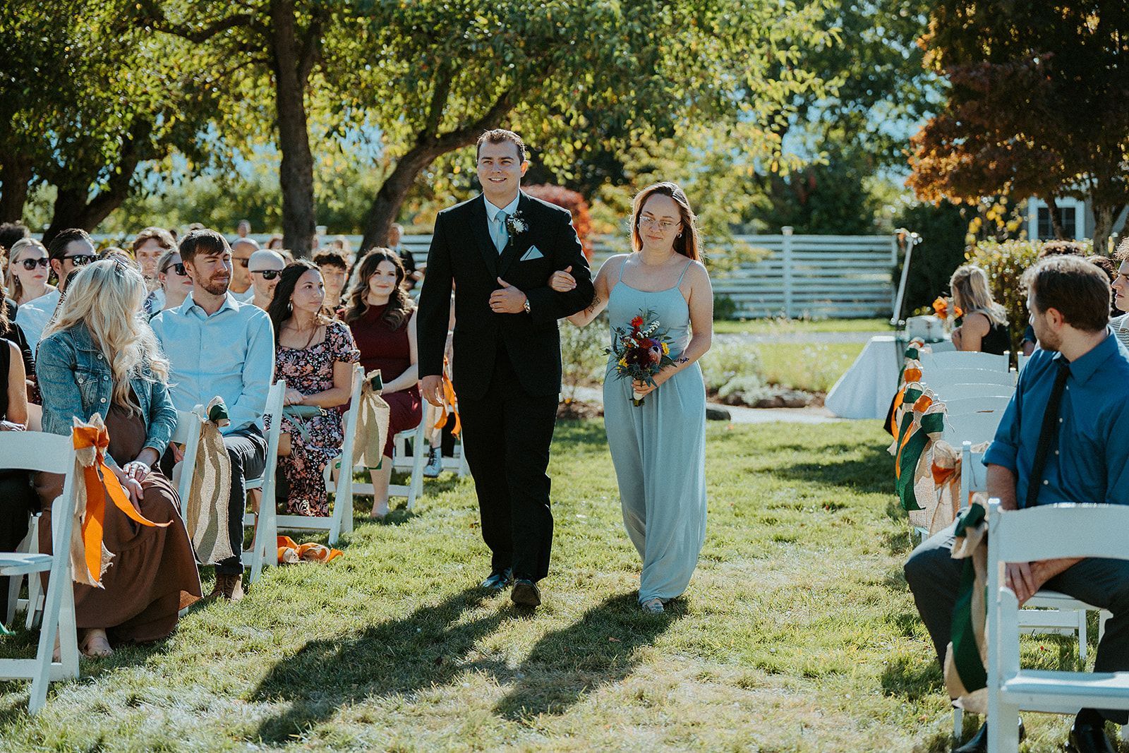 A groomsman and a bridesmaid are walking down the aisle at a wedding.