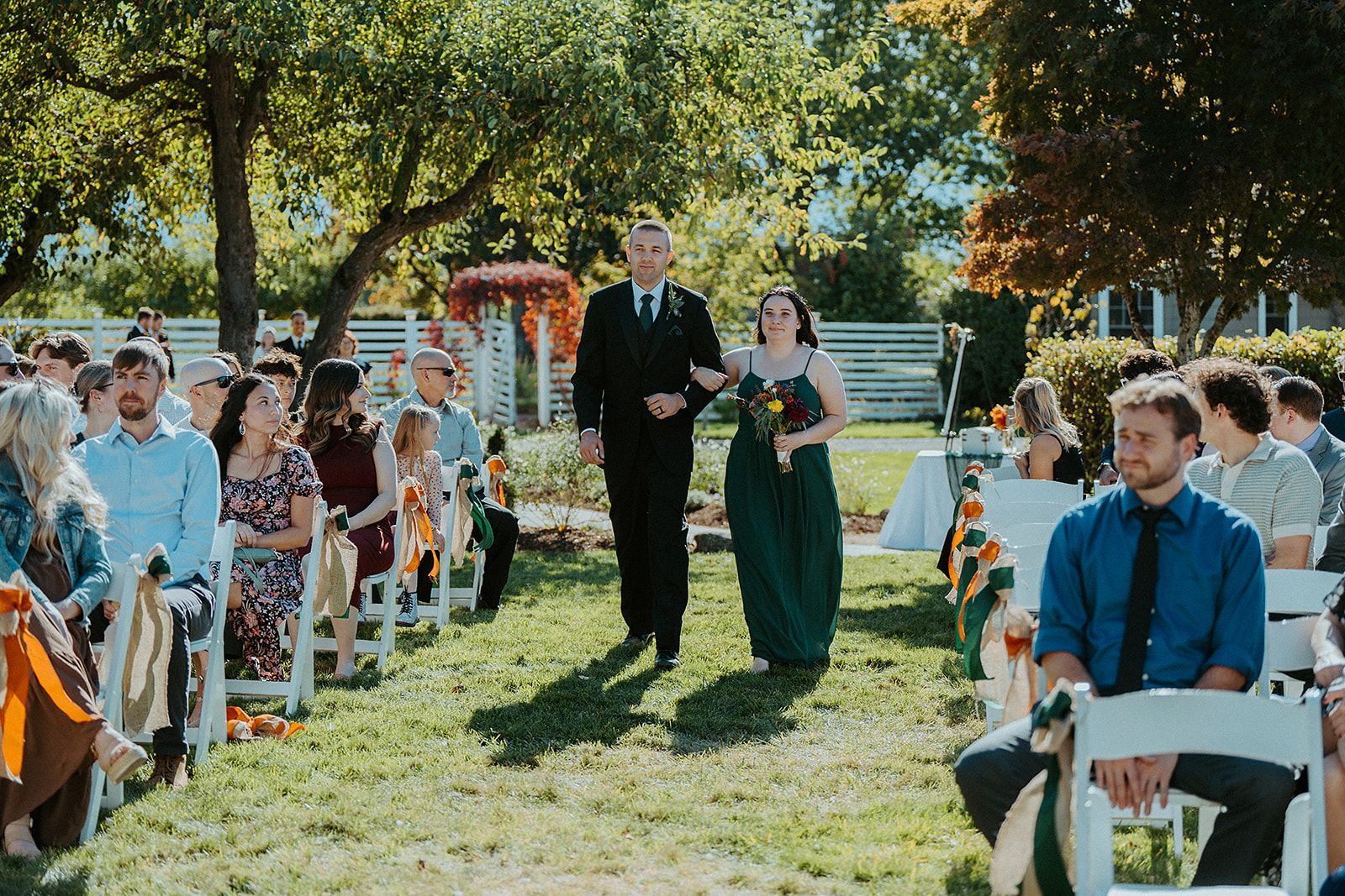 A groomsman and a bridesmaid are walking down the aisle at a wedding.