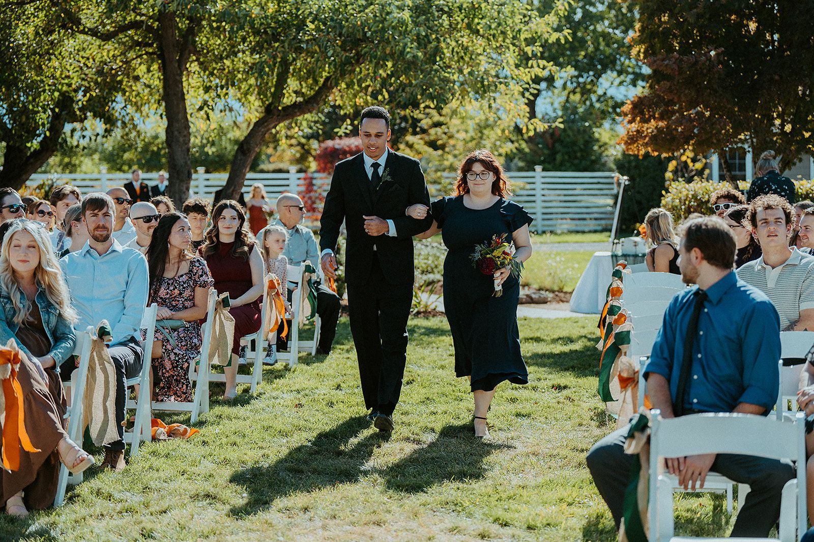 A groomsman and a bridesmaid are walking down the aisle at a wedding.