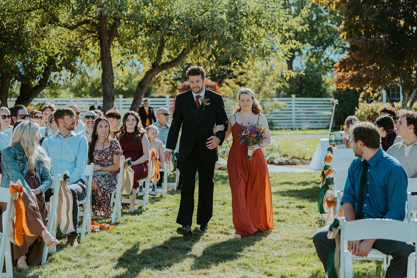 A groomsman and a bridesmaid are walking down the aisle at a wedding.