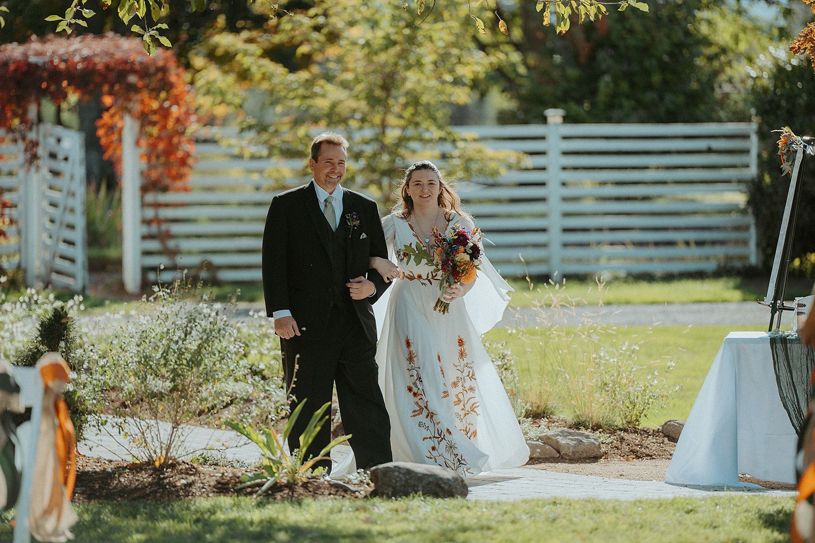 A bride and her father are walking down the aisle at their wedding.