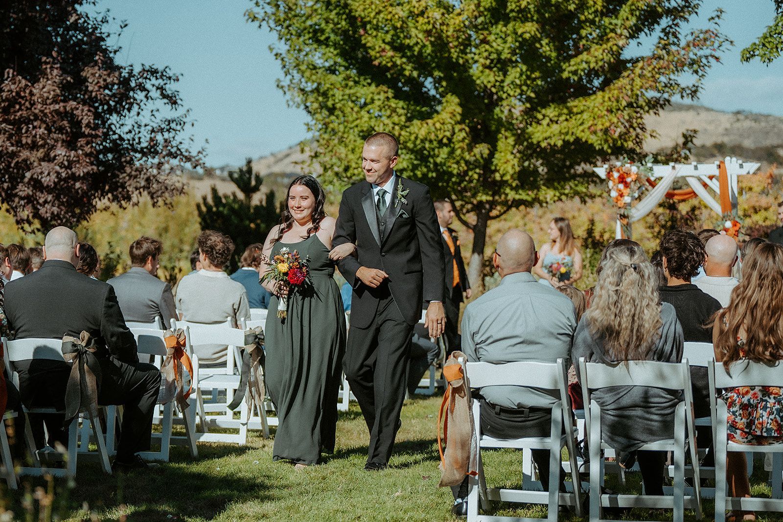 A groomsman and a bridesmaid are walking down the aisle at a wedding ceremony.