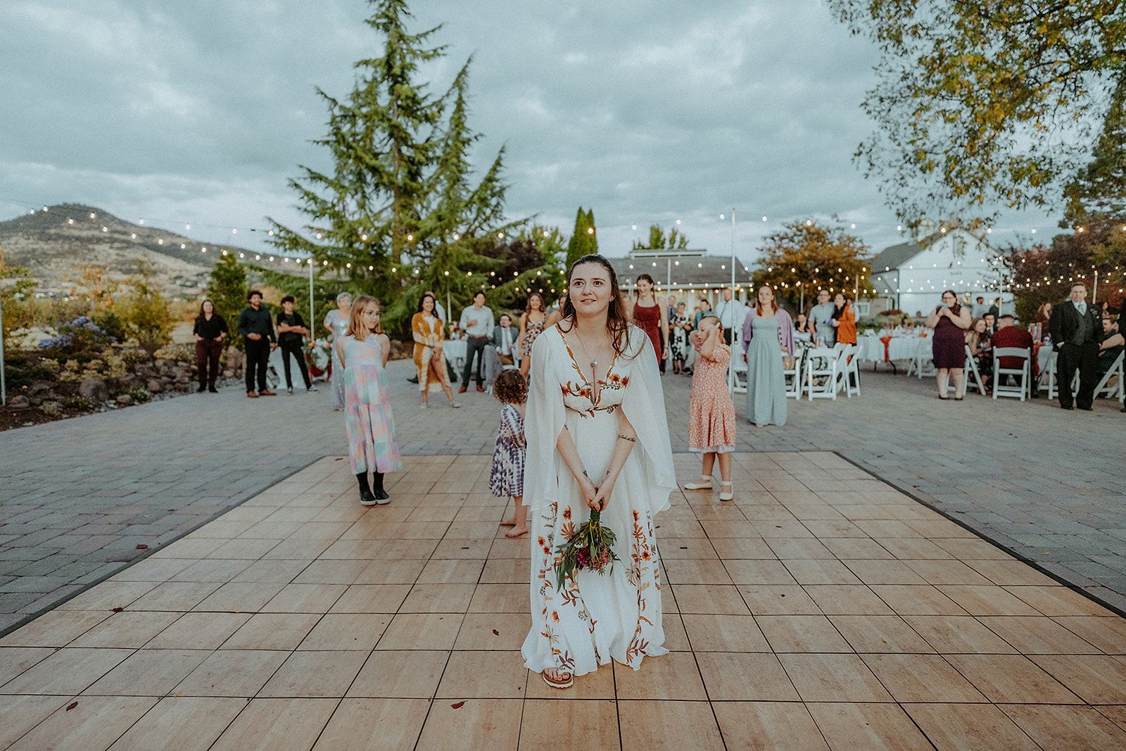 A bride is standing on a wooden floor holding a bouquet of flowers.