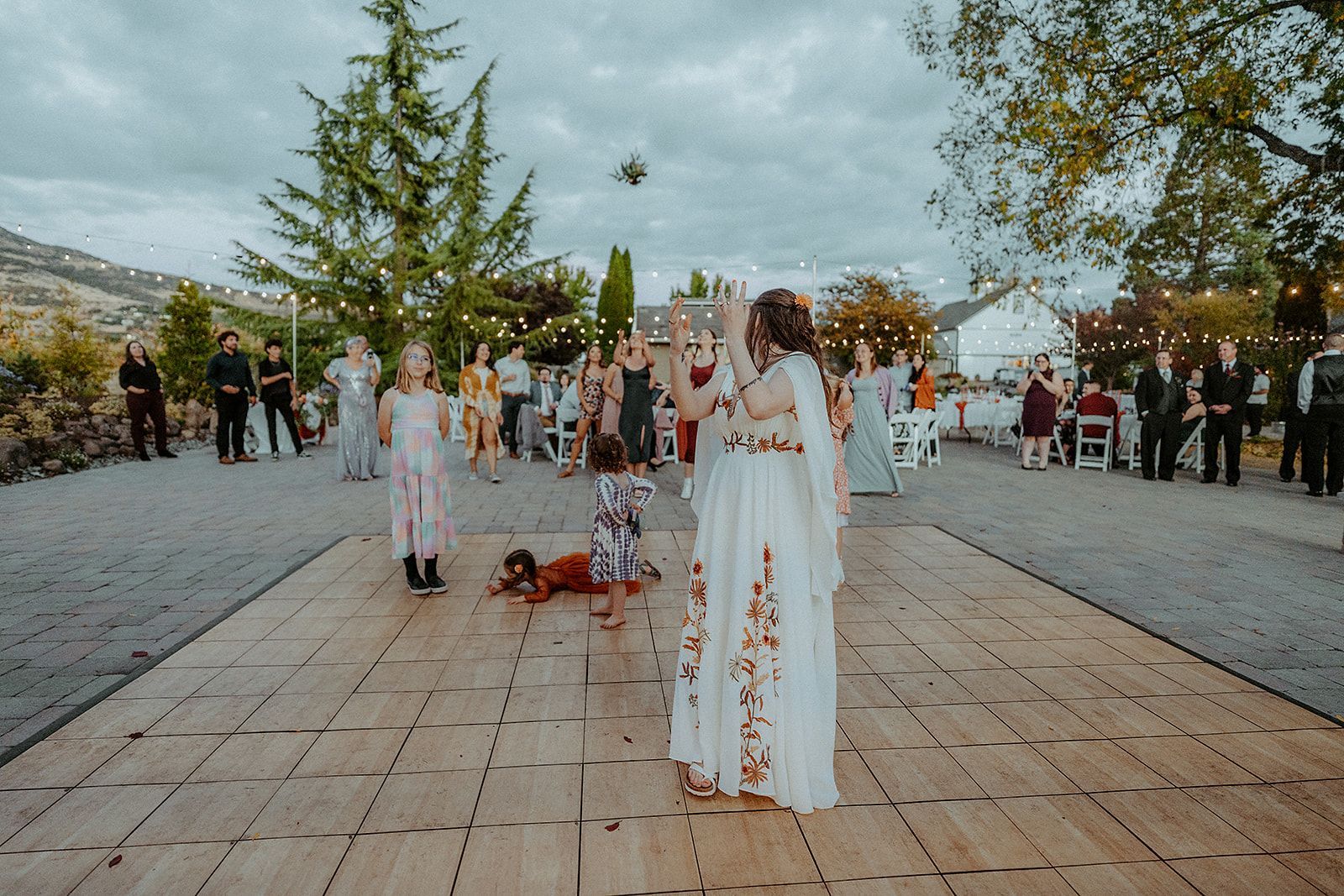 A woman in a white dress is throwing a bouquet of flowers at a wedding reception.