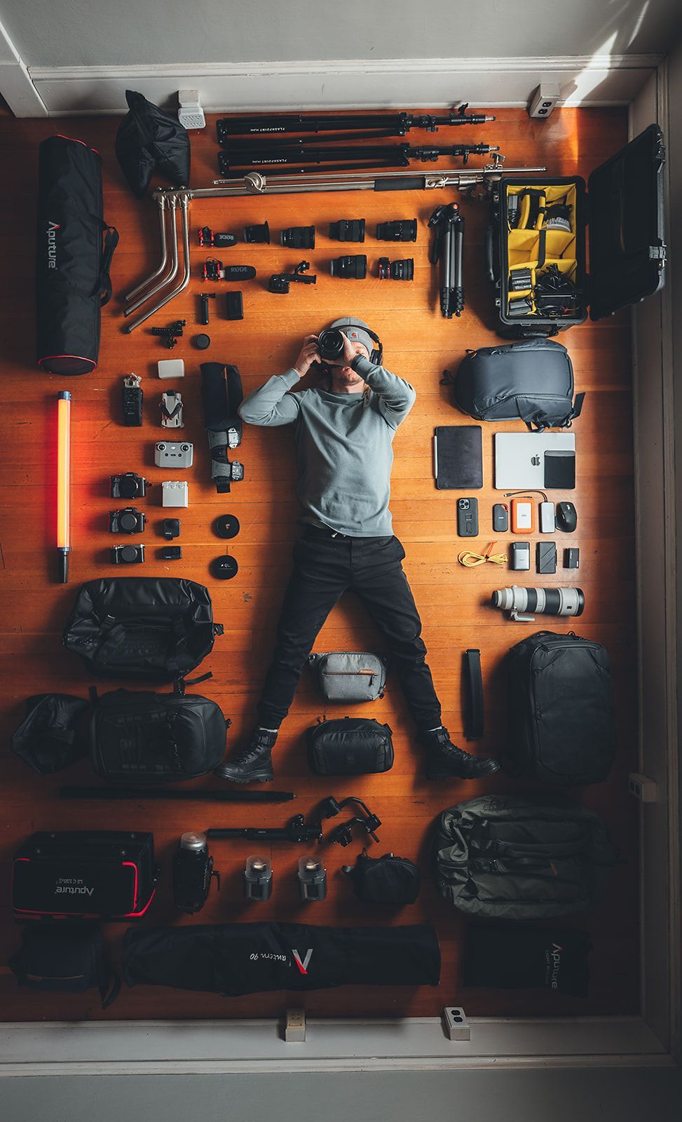 A man is laying on the floor surrounded by camera equipment.