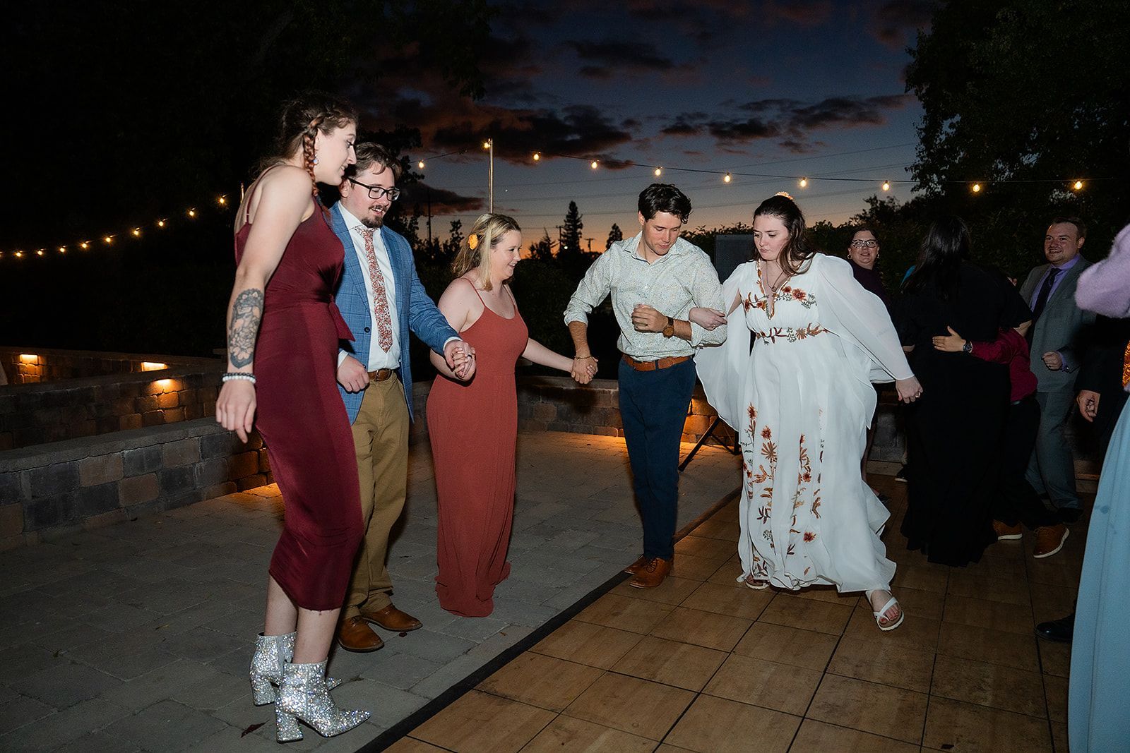A group of people are dancing together at a wedding reception.