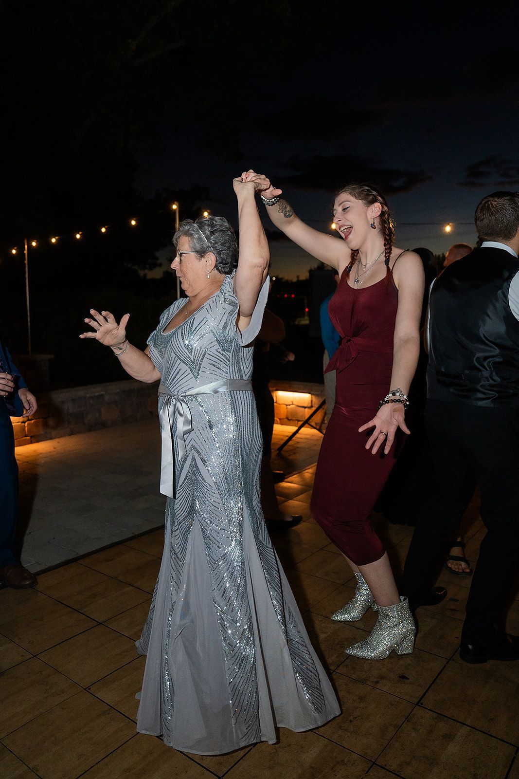 A woman in a silver dress is dancing with a woman in a red dress.