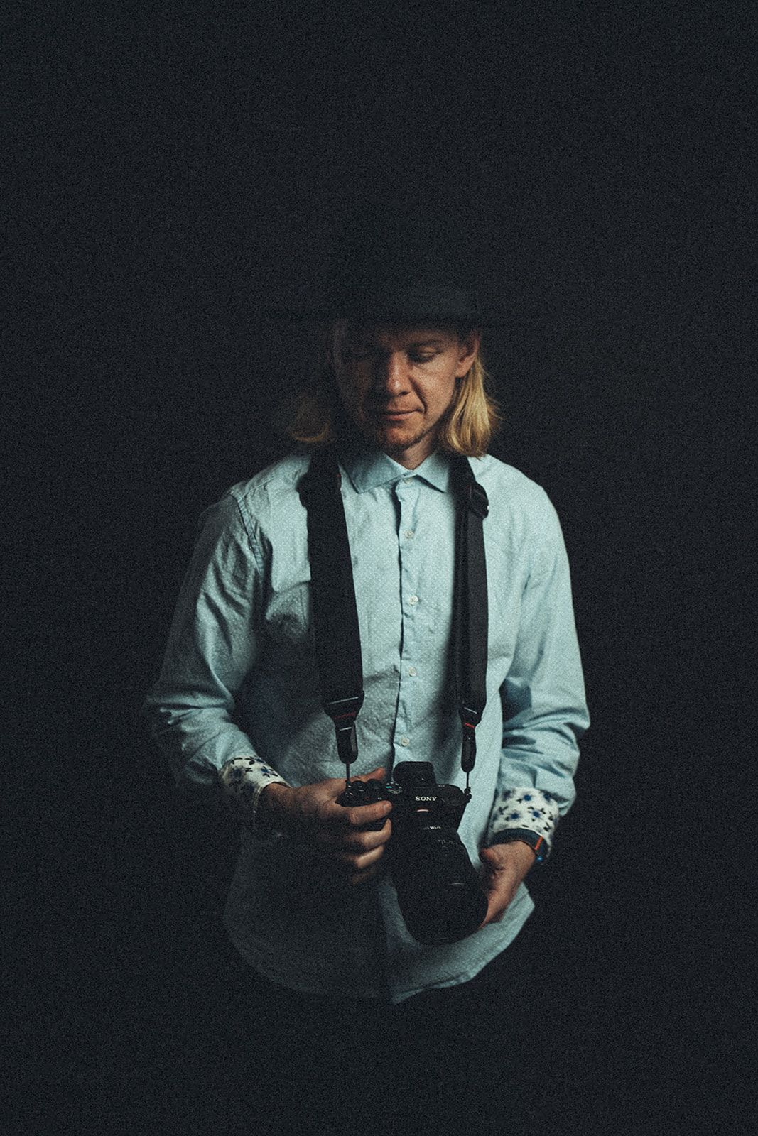 A man in a hat is holding a camera in his hand.